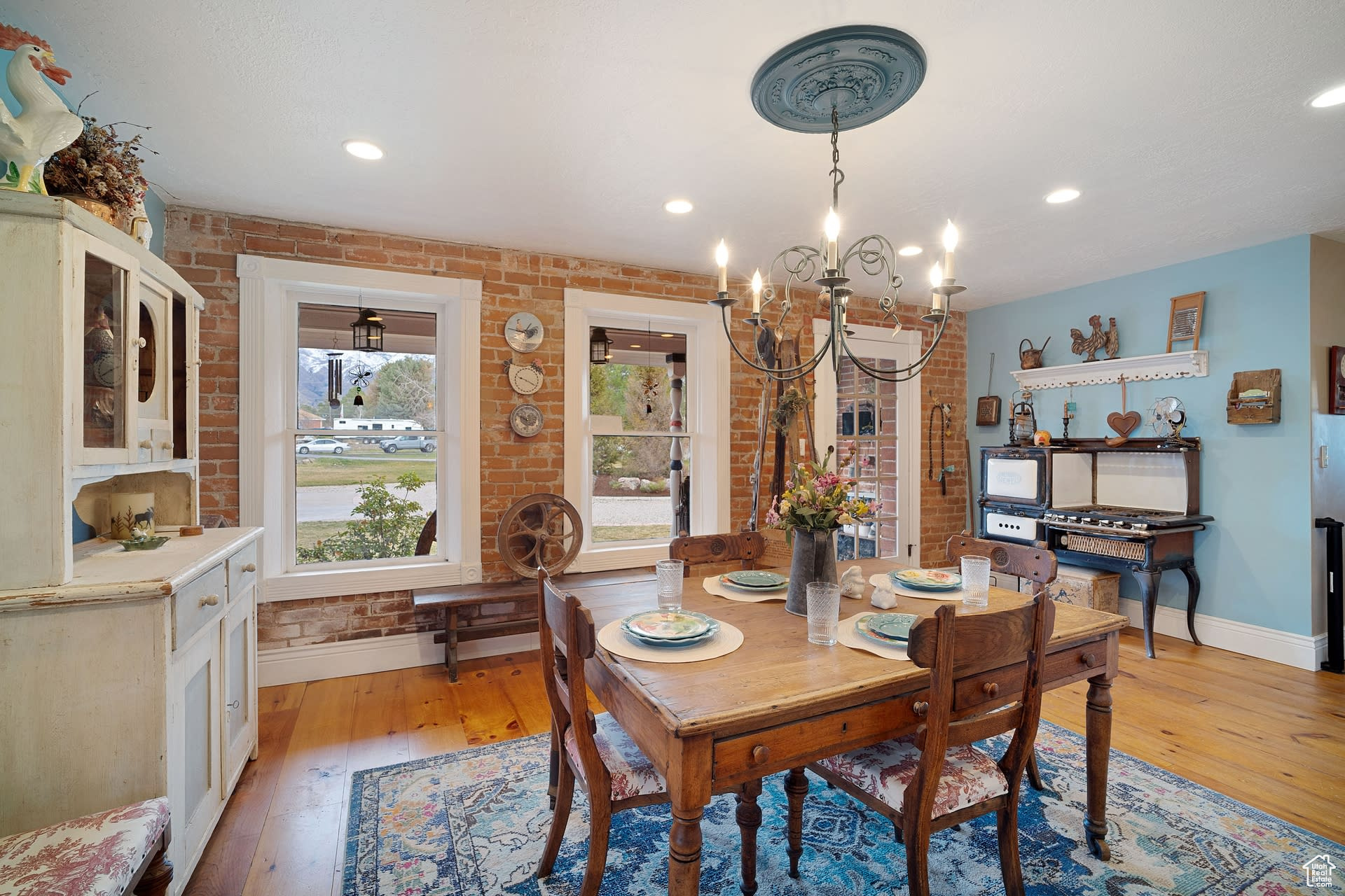 Dining area with an inviting chandelier, light hardwood / wood-style flooring, and brick wall
