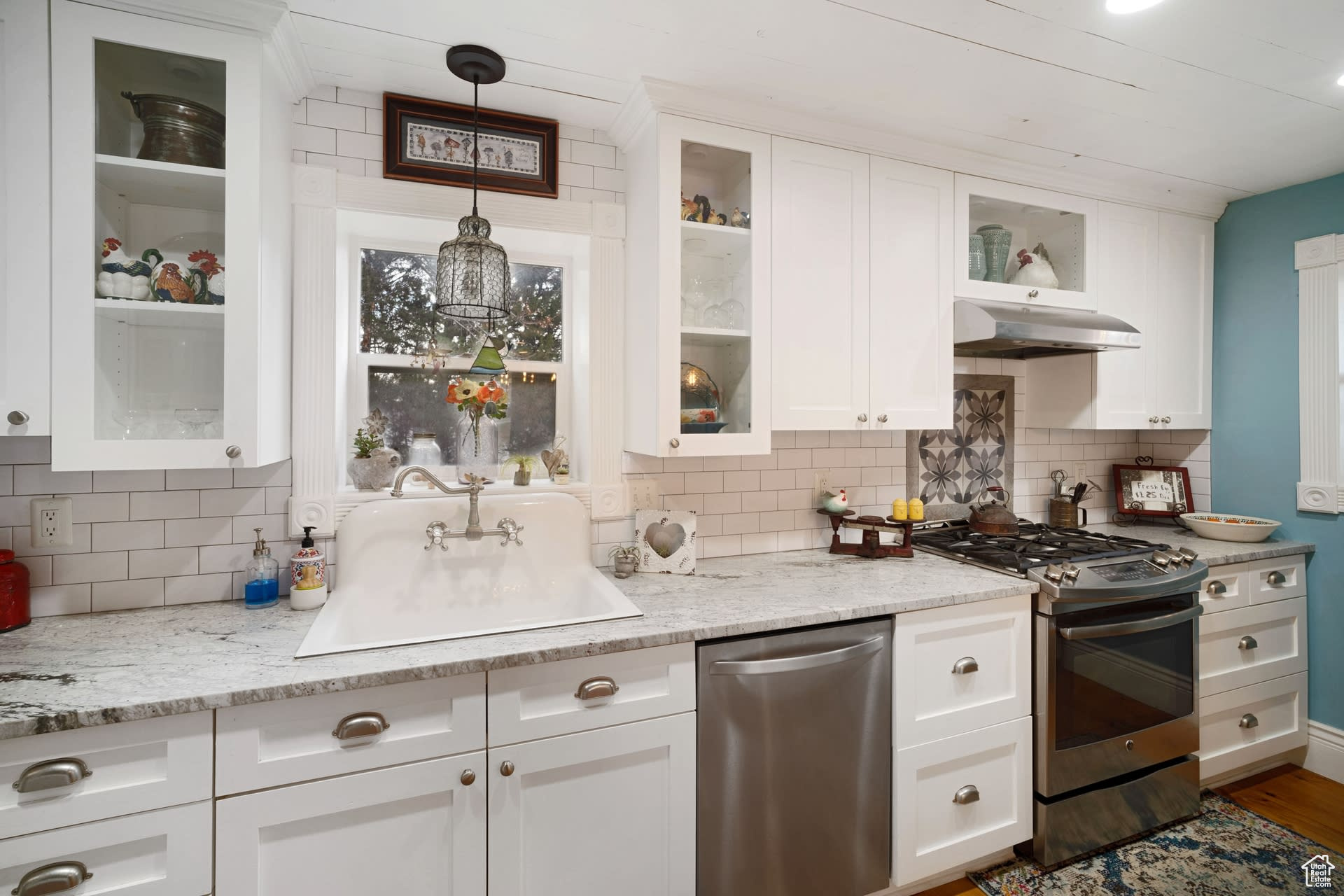 Kitchen with gas range oven, dishwasher, backsplash, and decorative light fixtures