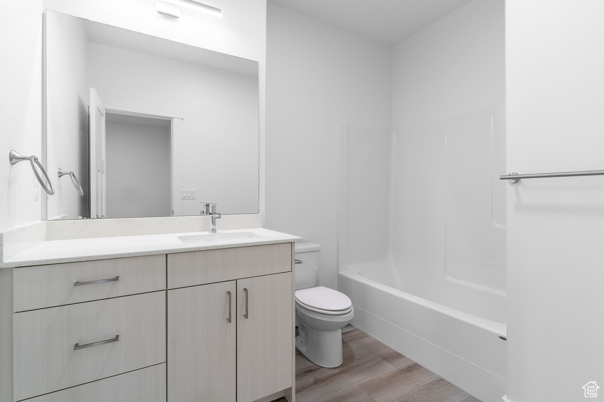 Full bathroom featuring vanity, toilet, wood-type flooring, and washtub / shower combination