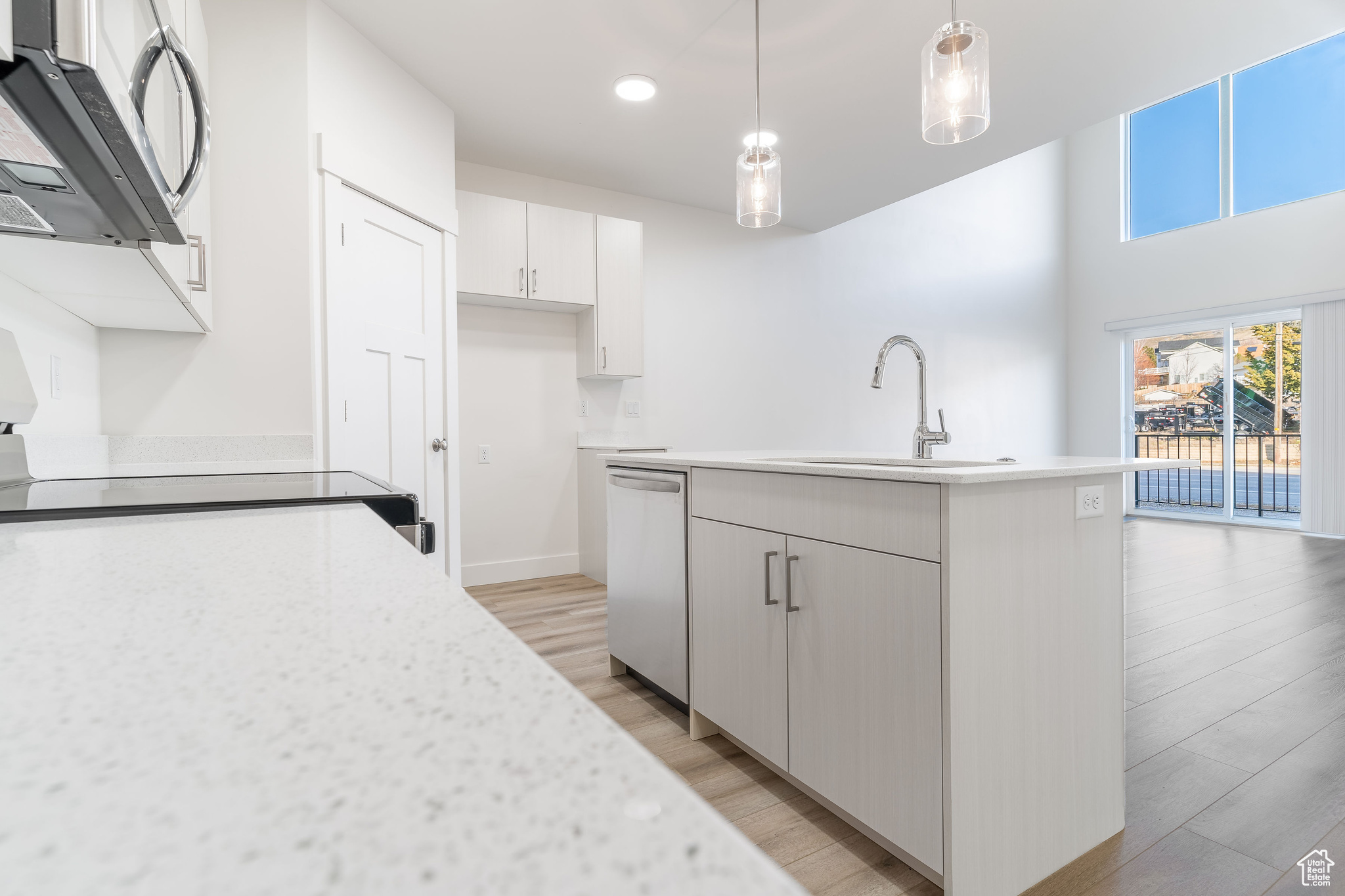 Kitchen featuring sink, a kitchen island with sink, appliances with stainless steel finishes, light hardwood / wood-style floors, and pendant lighting