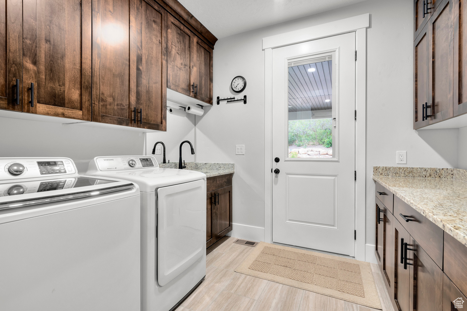 Clothes washing area with washing machine and dryer, cabinets, and light wood-type flooring