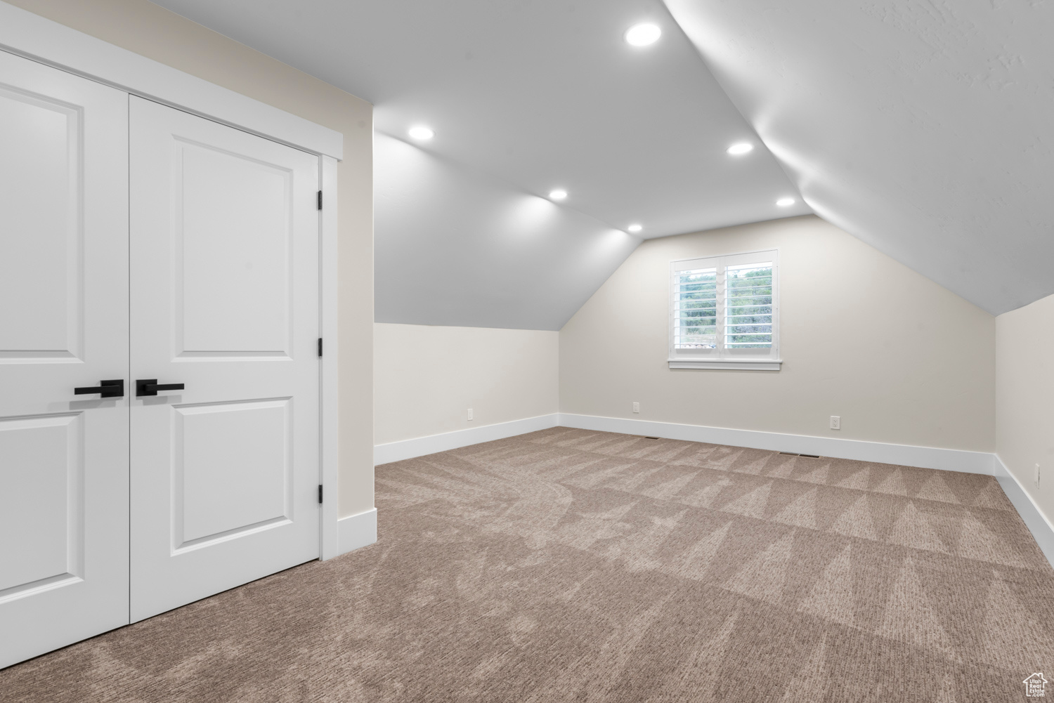 Additional living space featuring vaulted ceiling and light carpet