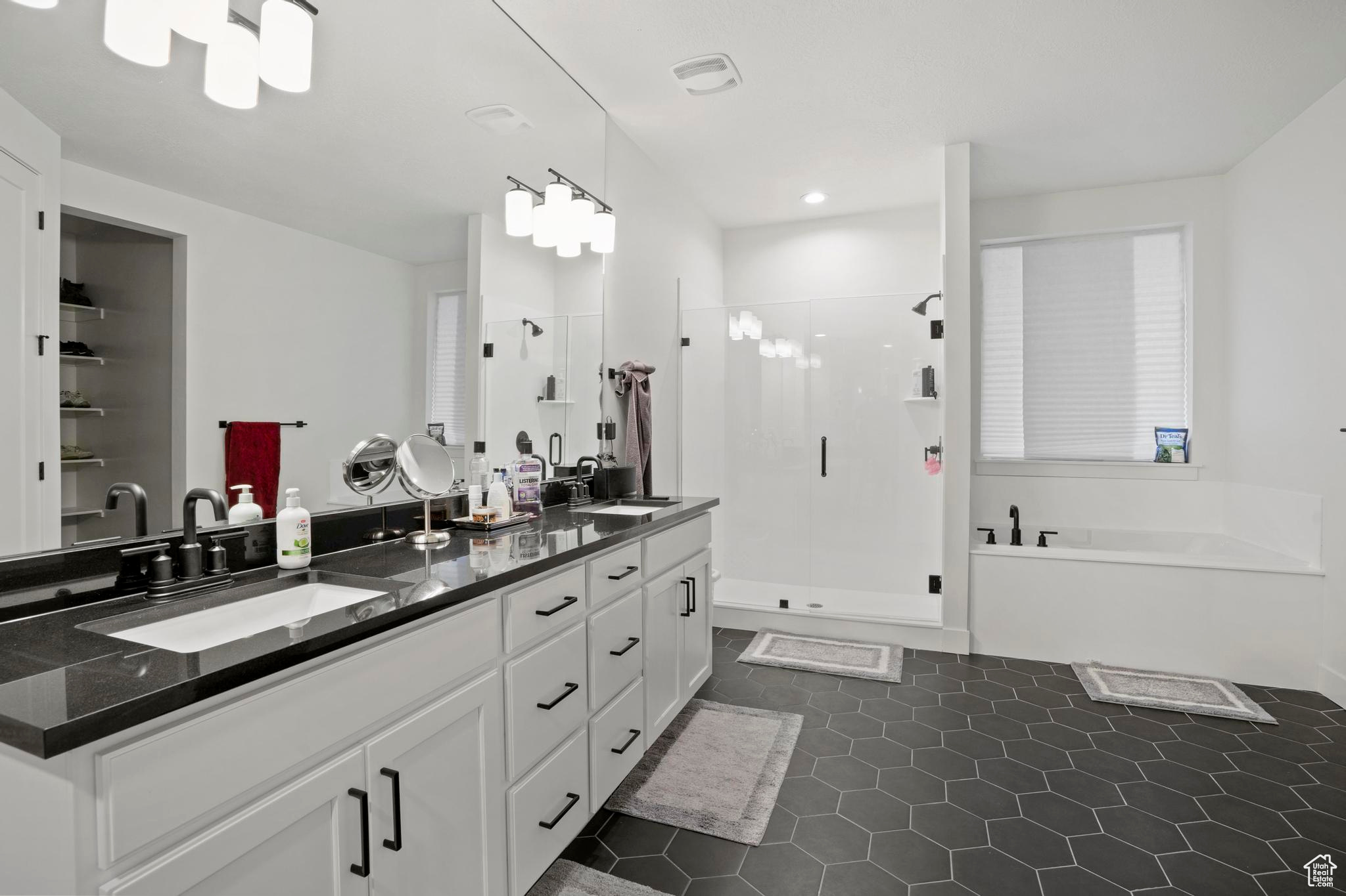 Bathroom featuring double sink vanity, tile floors, and separate shower and tub