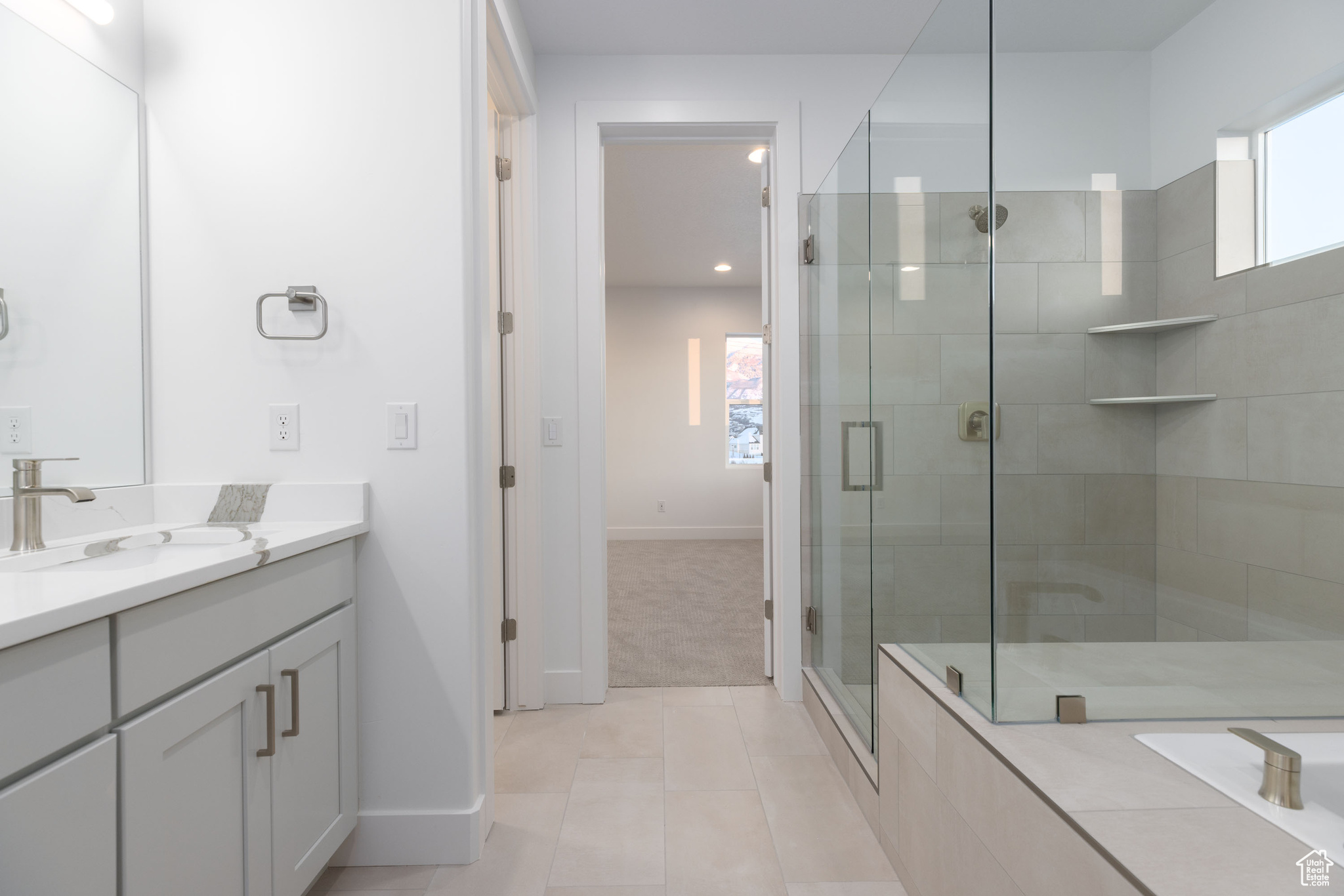 Bathroom featuring walk in shower, large vanity, and tile floors