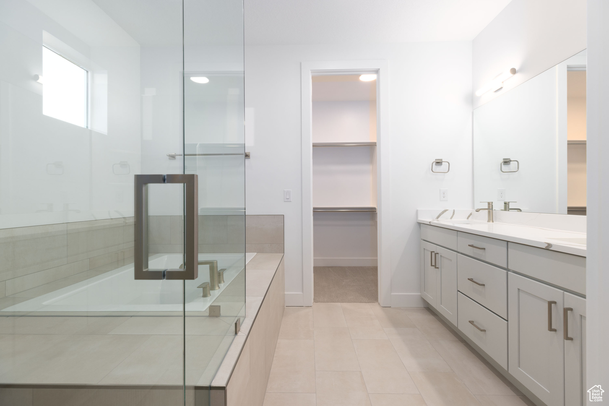 Bathroom with tile flooring, vanity with extensive cabinet space, and an enclosed shower