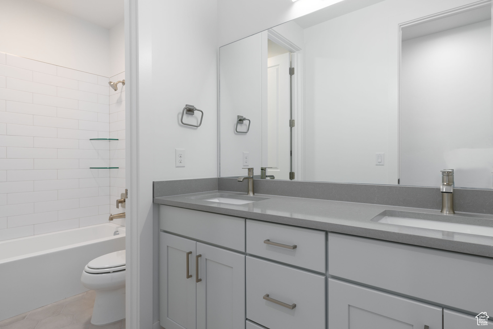 Full bathroom featuring tile floors, bathing tub / shower combination, dual vanity, and toilet