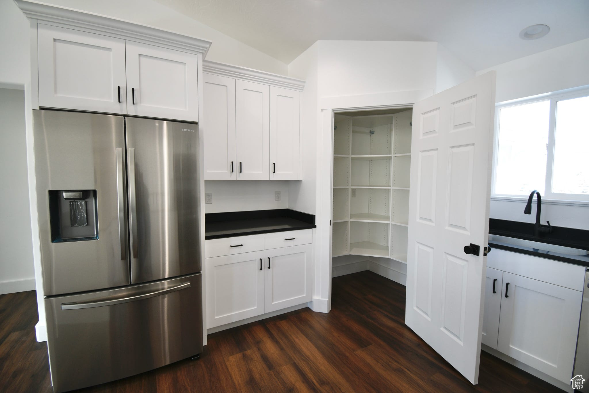 Kitchen featuring white cabinetry, stainless steel fridge with ice dispenser, sink, and dark hardwood / wood-style floors