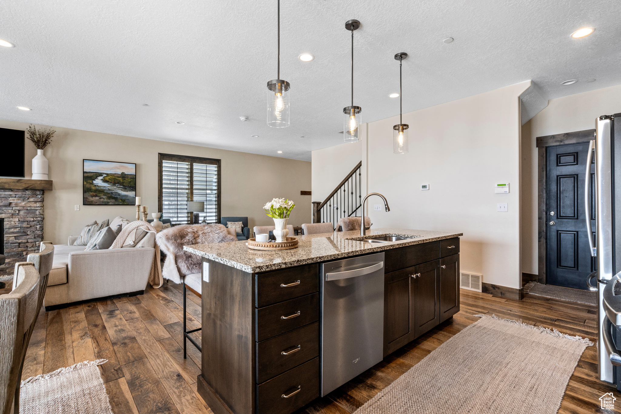 Kitchen featuring pendant lighting, an island with sink, dark hardwood / wood-style flooring, and dishwasher