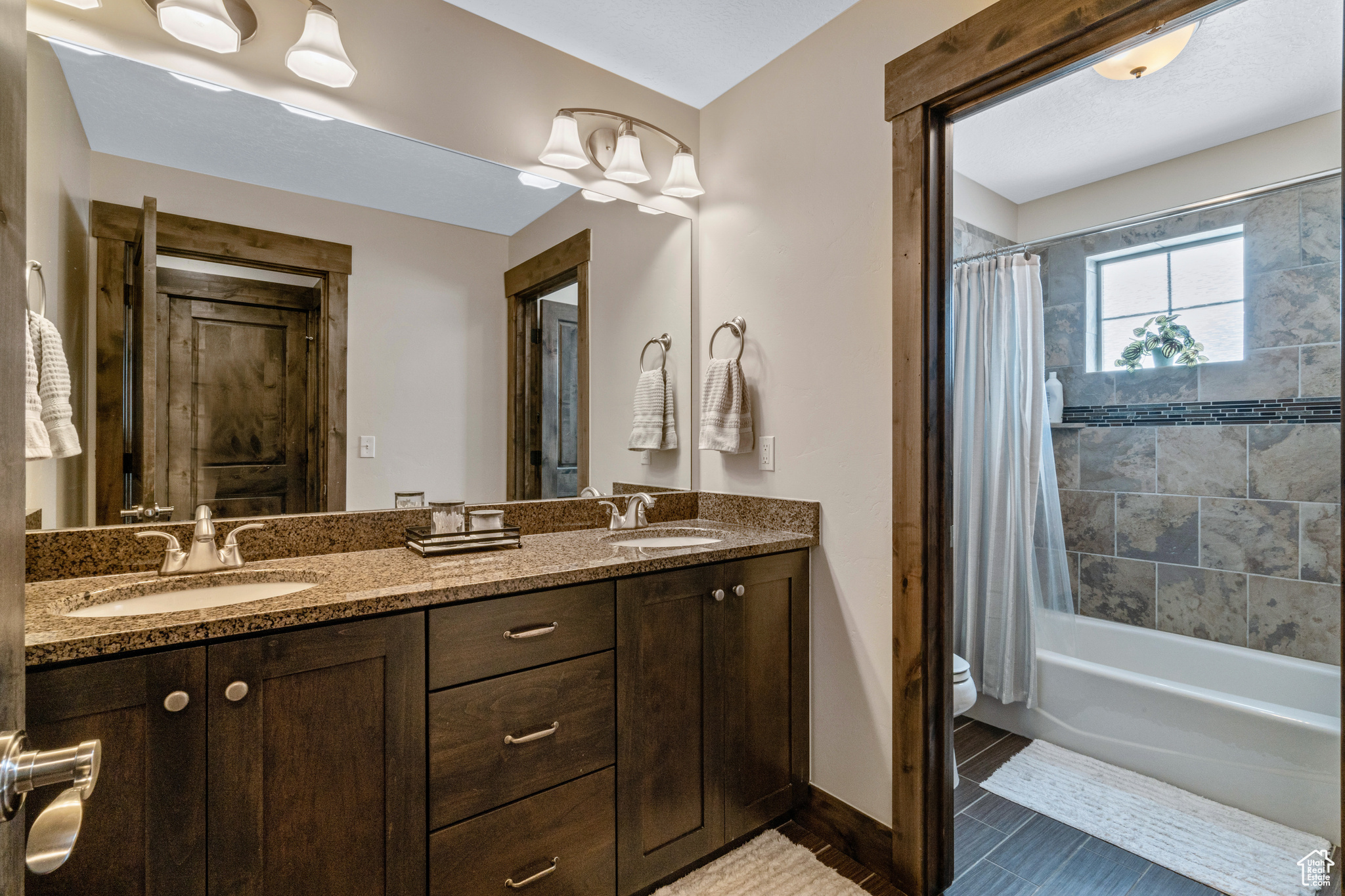 Full bathroom featuring toilet, tile flooring, shower / bath combo, and dual bowl vanity