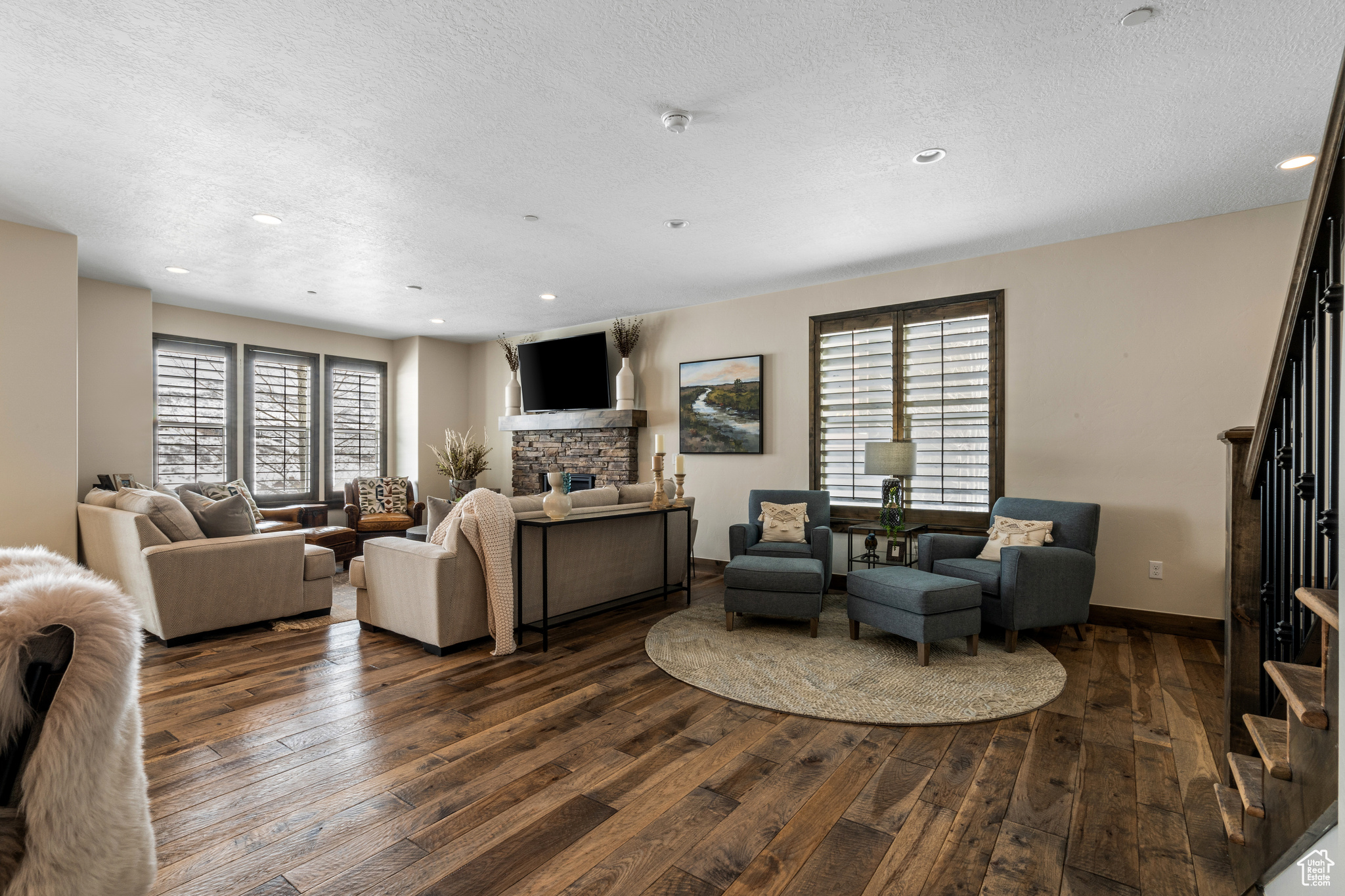 Living room with dark hardwood / wood-style flooring, a fireplace, a textured ceiling, and a healthy amount of sunlight