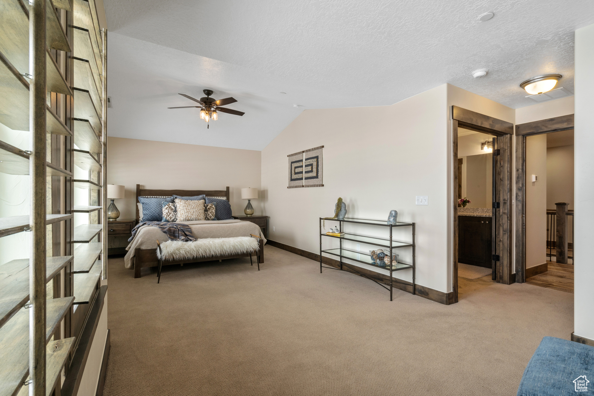 Bedroom with lofted ceiling, carpet floors, connected bathroom, and ceiling fan