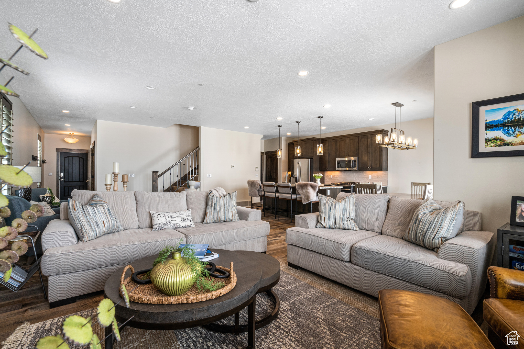 Living room with a chandelier, a textured ceiling, and dark wood-type flooring