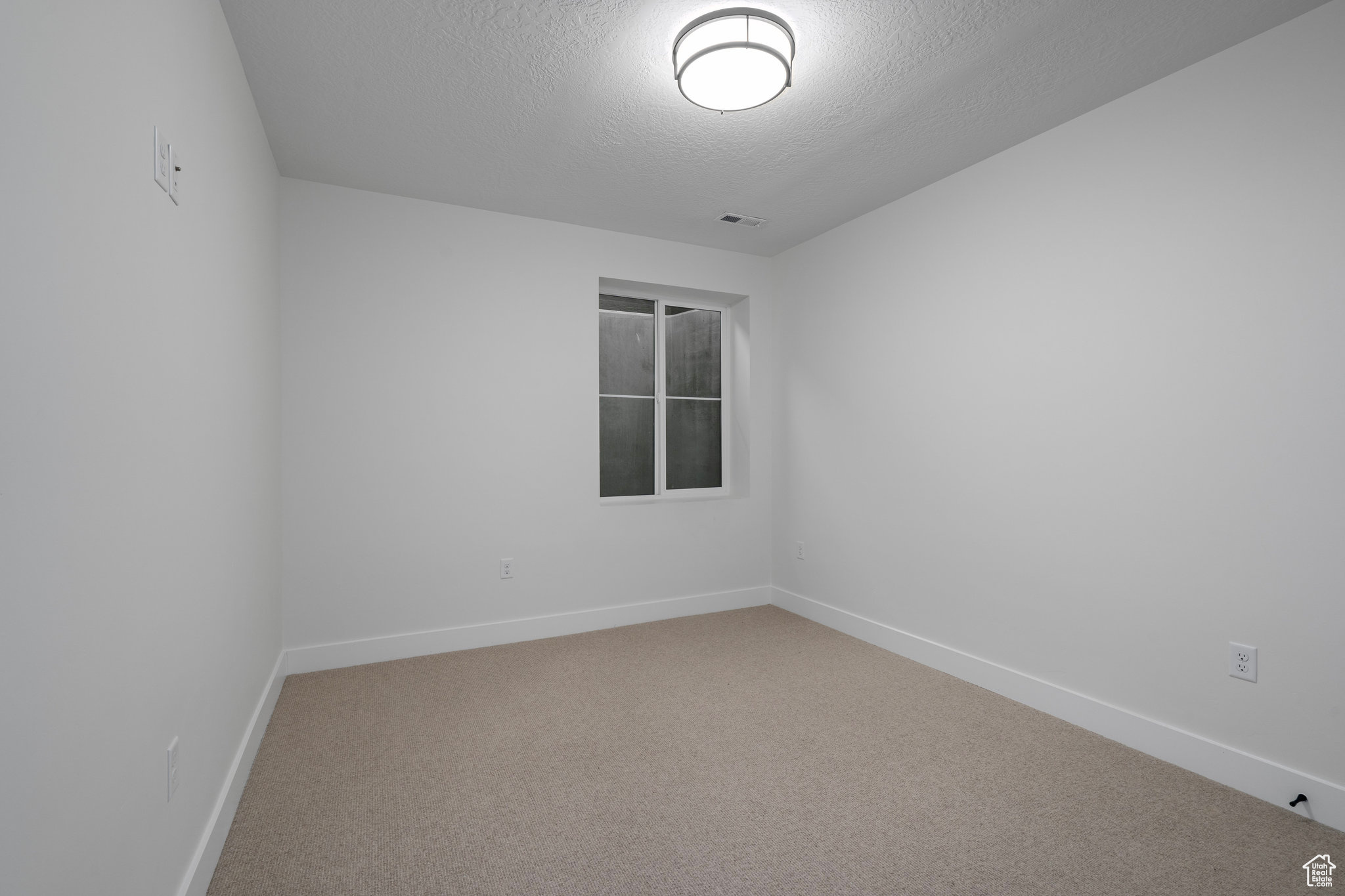 Bedroom featuring light carpet and a textured ceiling