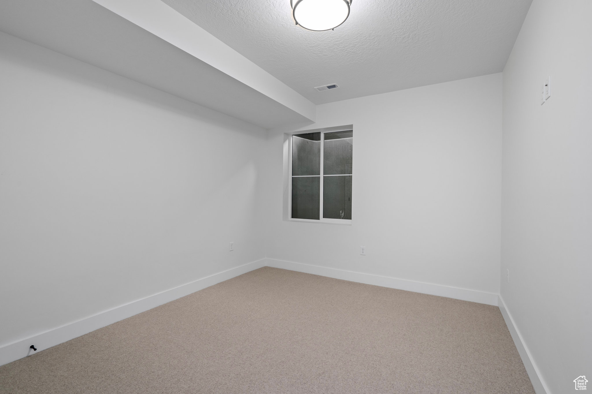 Bedroom featuring light colored carpet and a textured ceiling