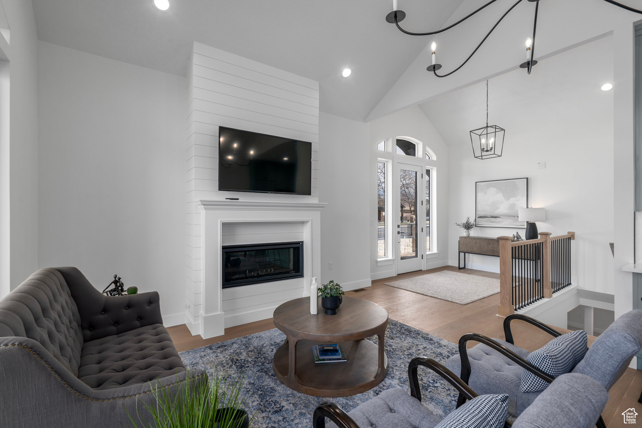 Living room featuring high vaulted ceiling, a notable chandelier, a large fireplace, and dark hardwood / wood-style floors