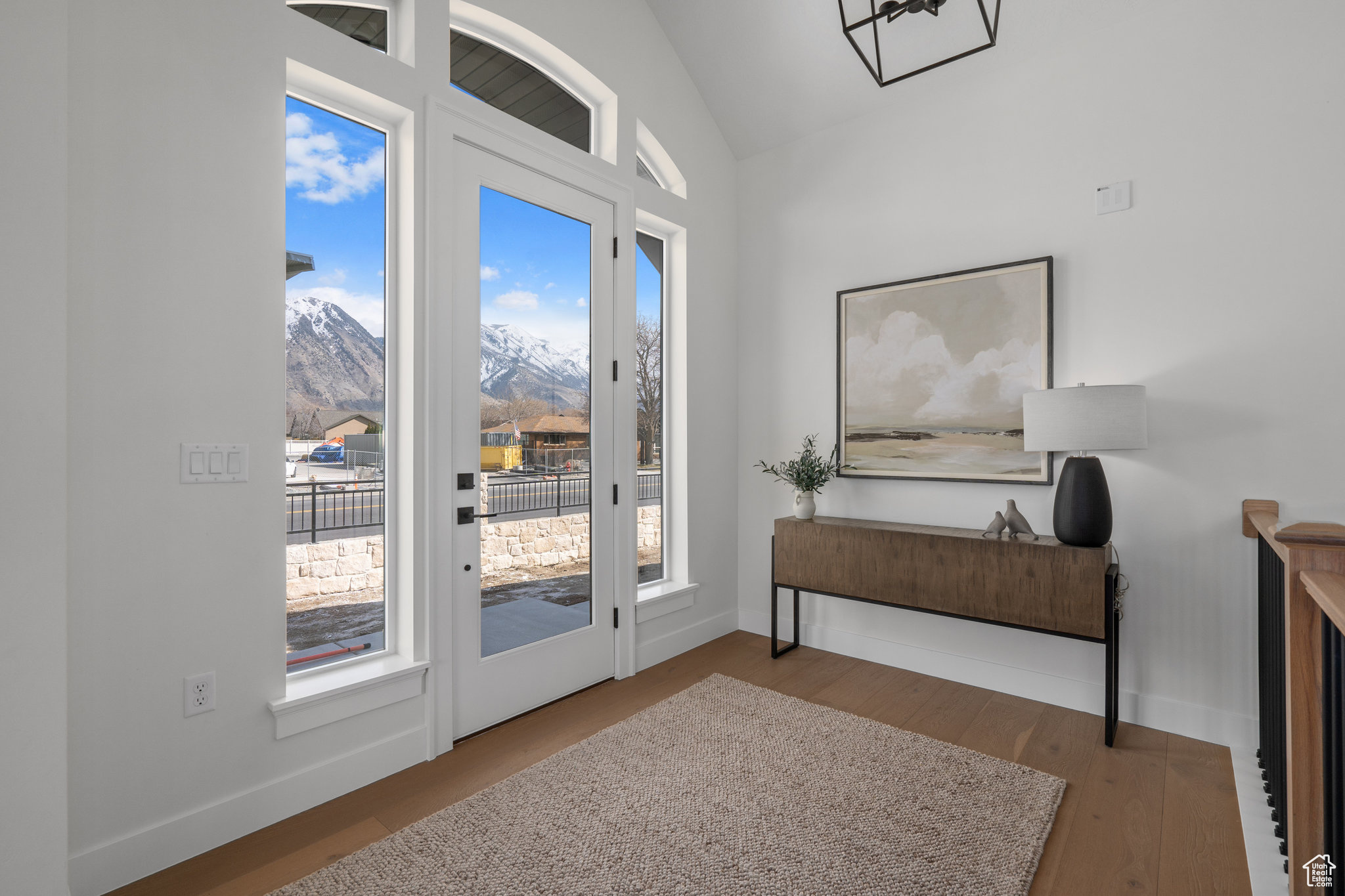 Doorway to outside featuring a mountain view, vaulted ceiling, dark wood-type flooring, and a healthy amount of sunlight