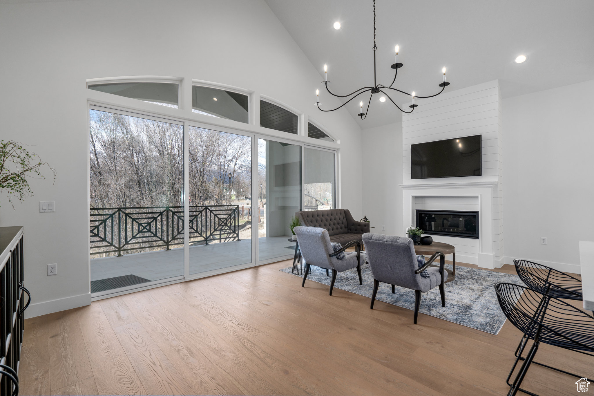 Sitting room featuring high vaulted ceiling, light hardwood / wood-style flooring, a fireplace, and a chandelier