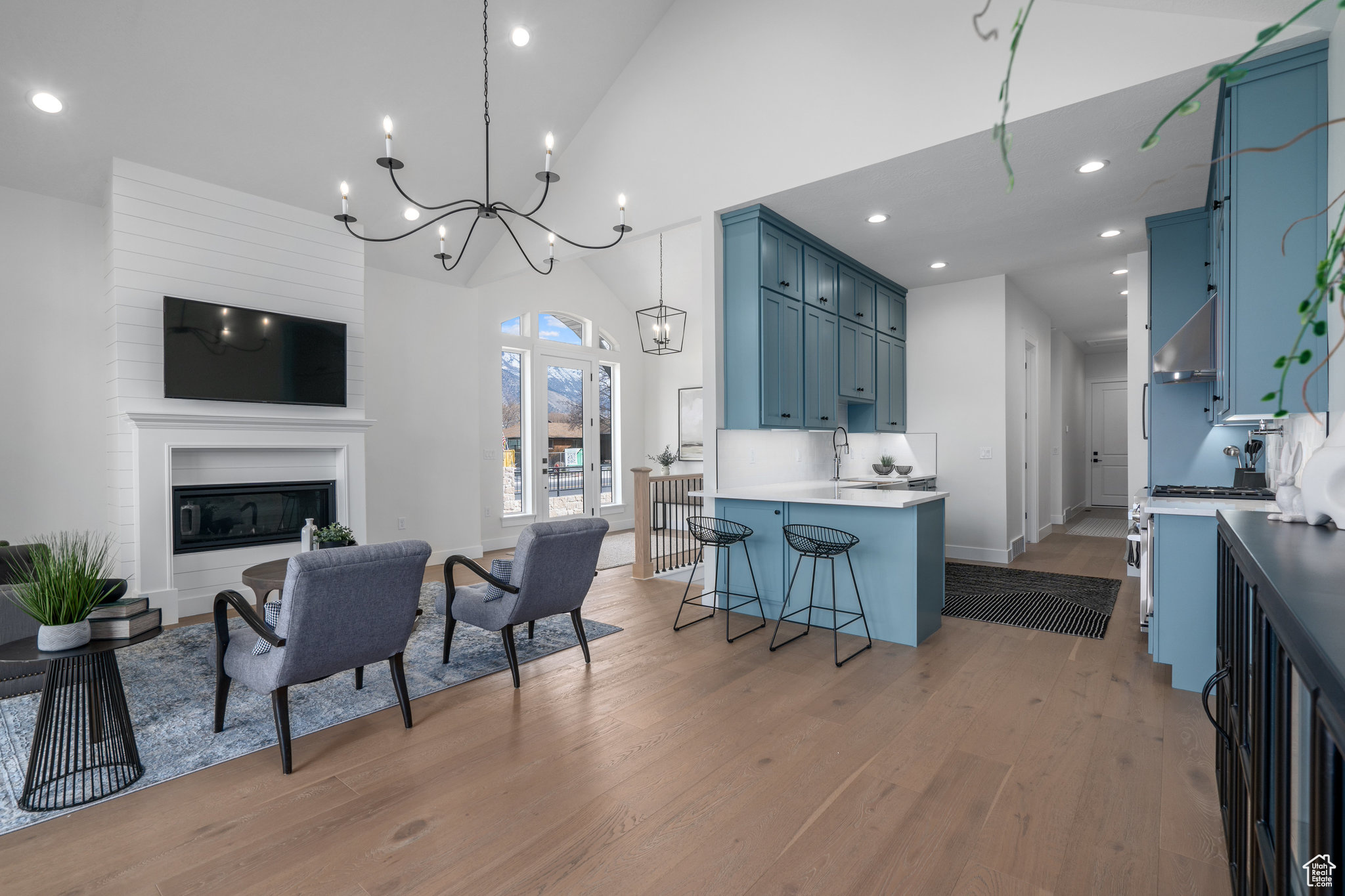 Living room featuring a large fireplace, an inviting chandelier, hardwood / wood-style flooring, and high vaulted ceiling