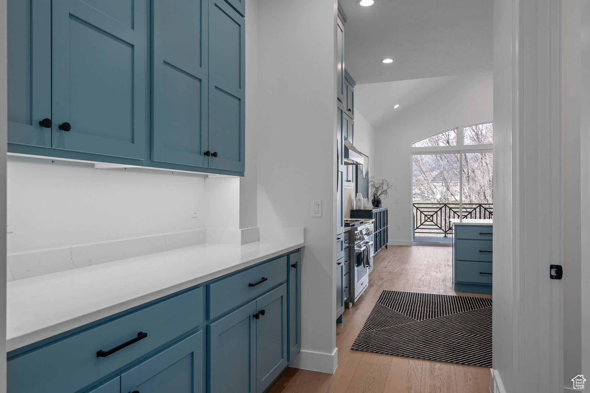 Kitchen with high end stainless steel range, vaulted ceiling, light hardwood / wood-style flooring, and blue cabinetry