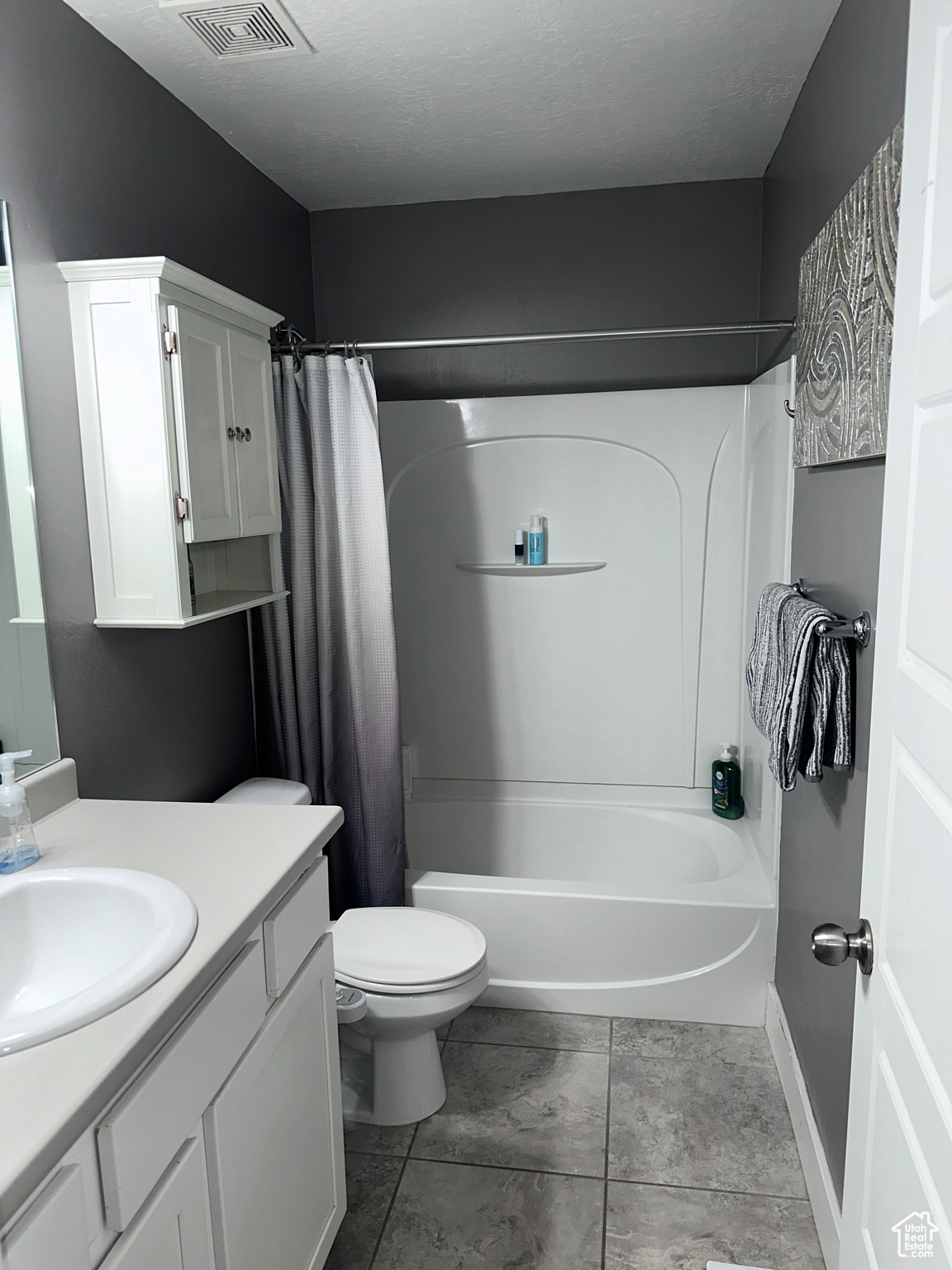 Full bathroom with shower / bath combination with curtain, tile floors, toilet, and vanity