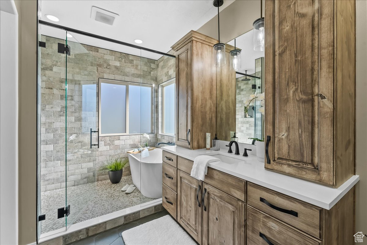 Bathroom with a shower with spa like tub and separate walk in shower. European glass shower door, tile floors, and vanity