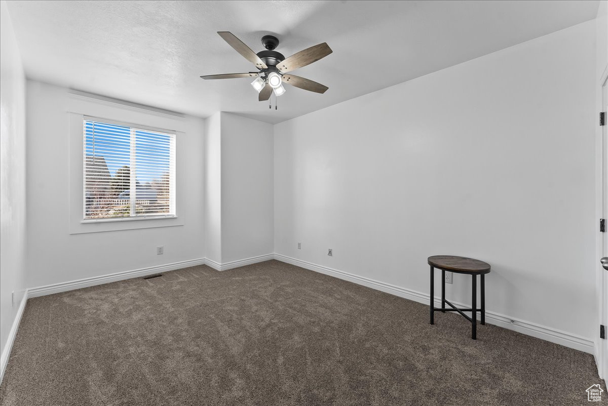 Carpeted spare bedroom featuring ceiling fan