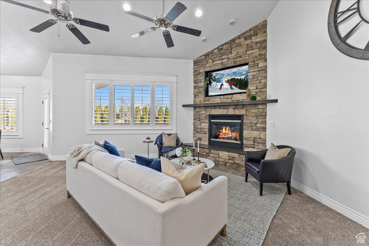 Carpeted living room featuring vaulted ceiling, plenty of natural light, and ceiling fan