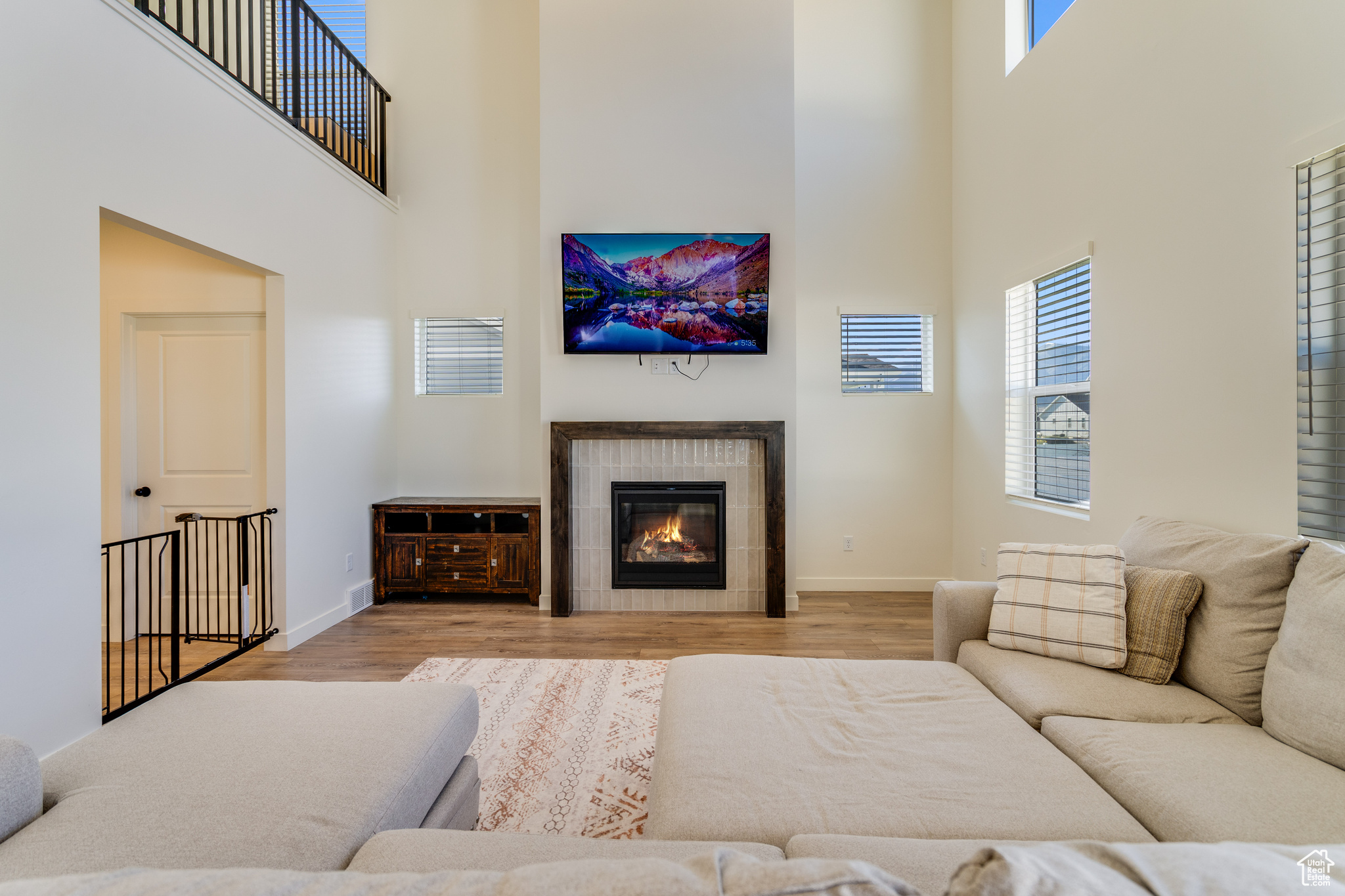 Living room with a fireplace, light hardwood / wood-style flooring, and a towering ceiling