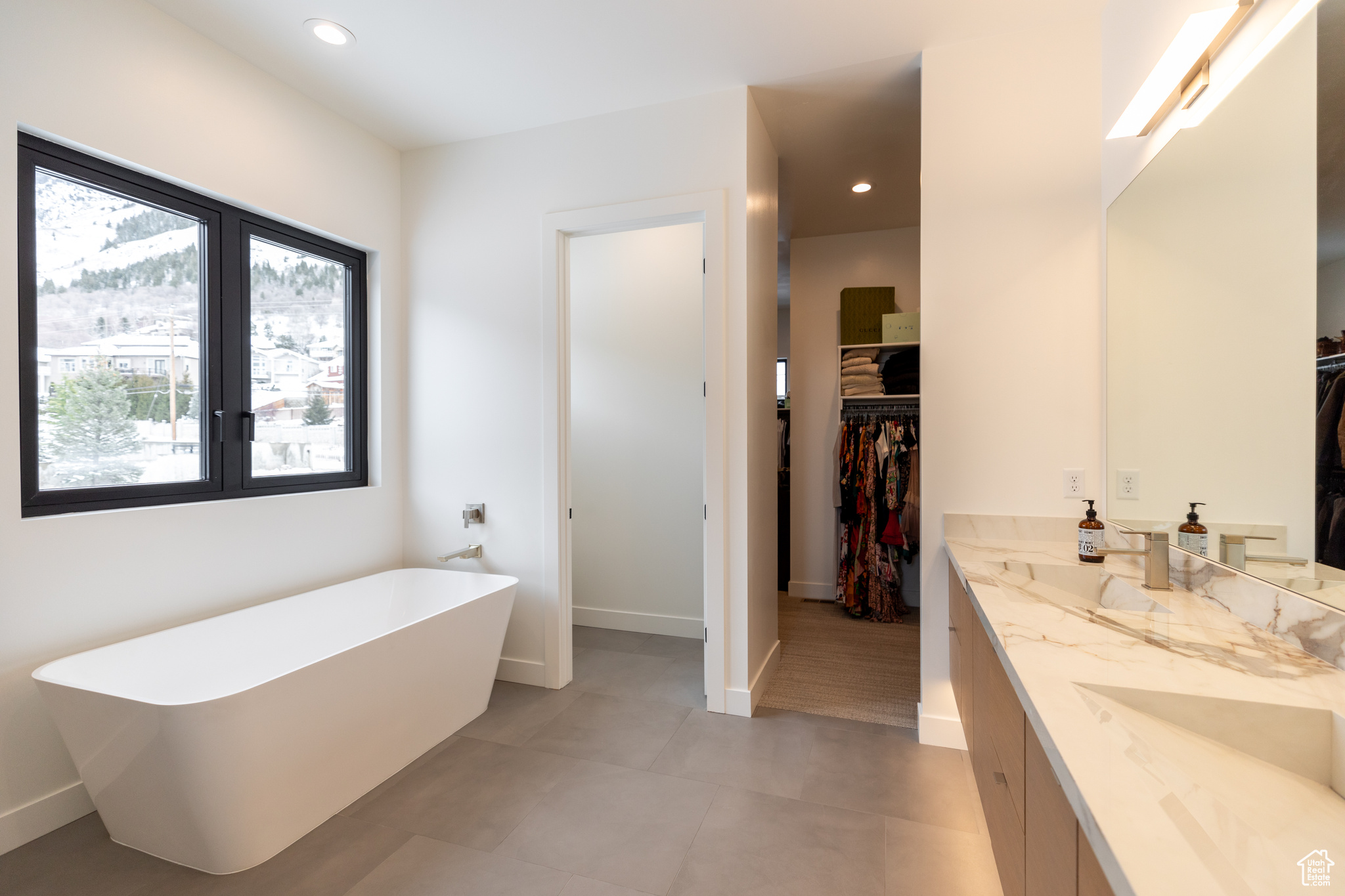 Bathroom featuring tile flooring, dual vanity, and a bathtub