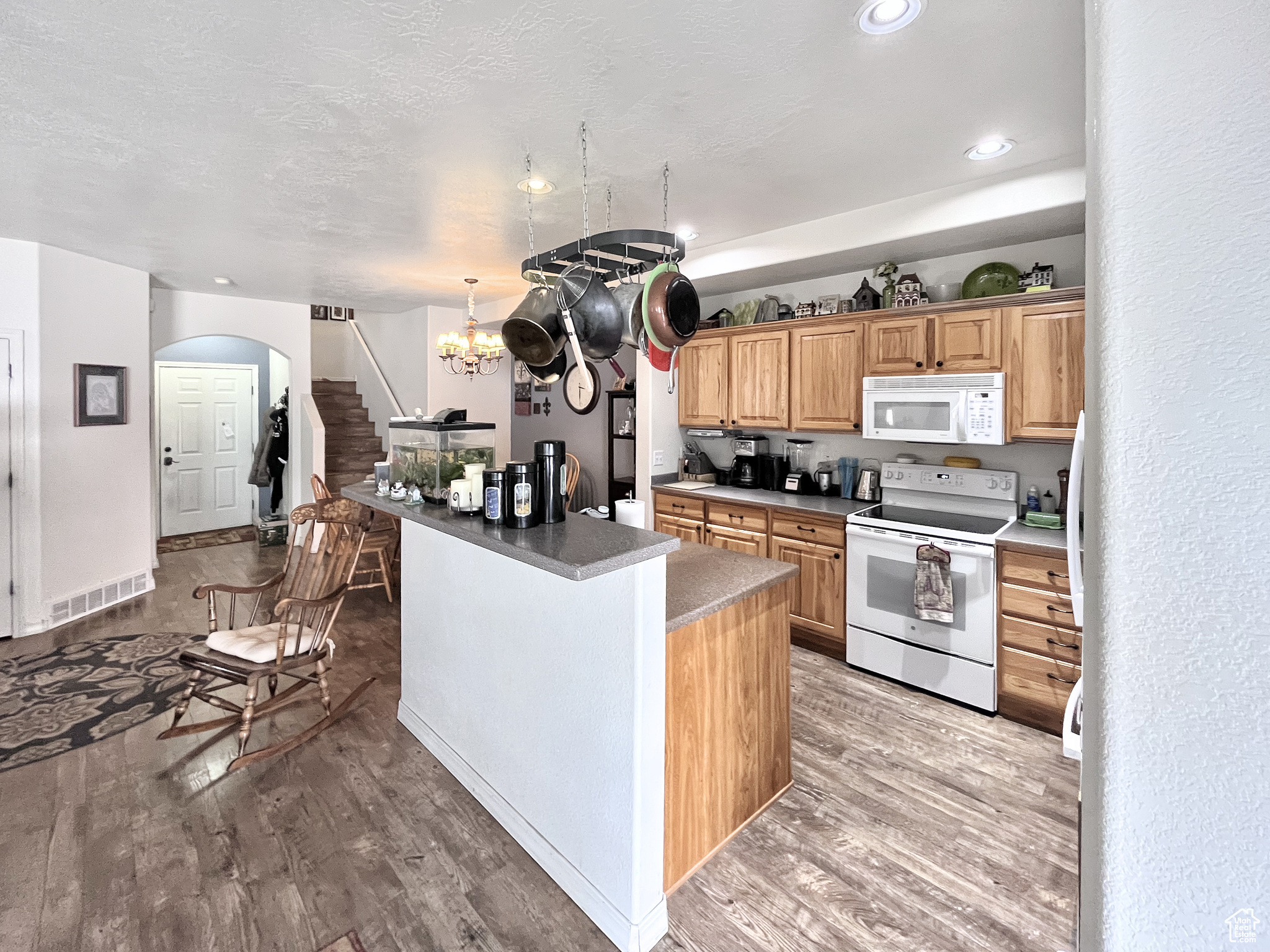 Kitchen featuring maple cabinets, convenient appliances, a kitchen island, and beautiful flooring