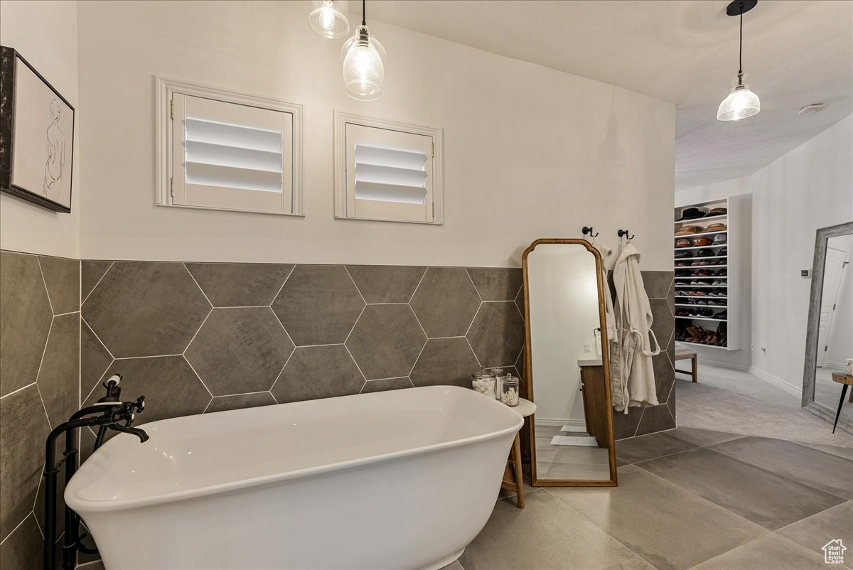 Bathroom featuring tile walls, a bathtub, and tile floors