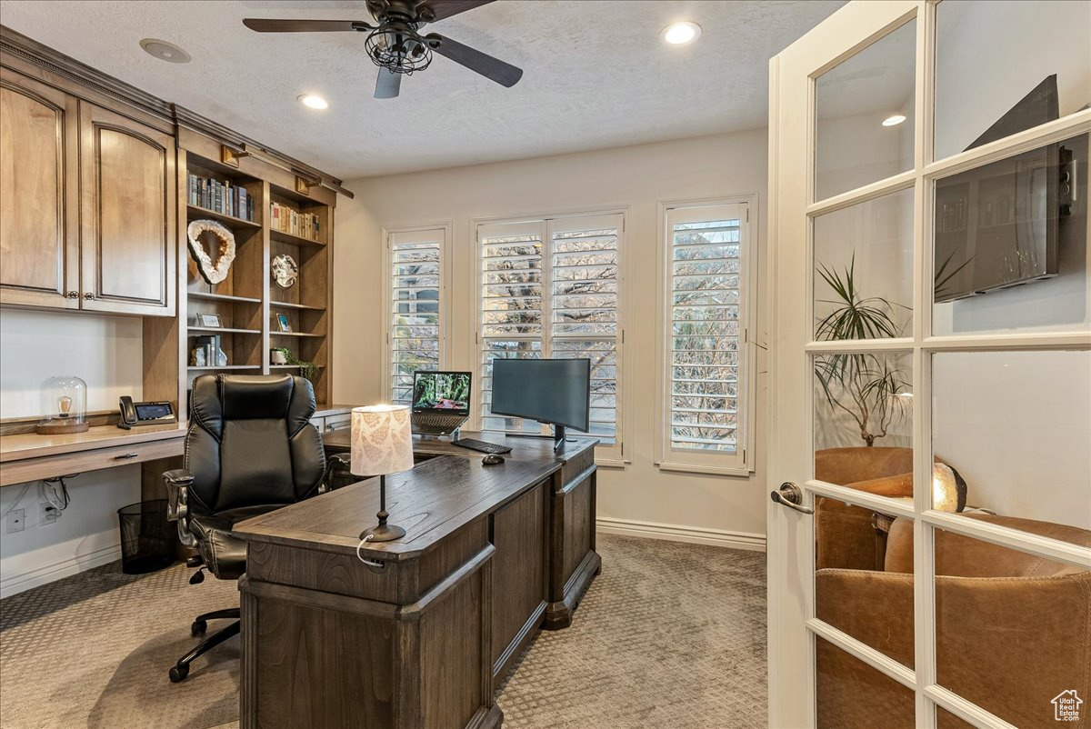 Office with built in desk, dark carpet, a textured ceiling, and ceiling fan