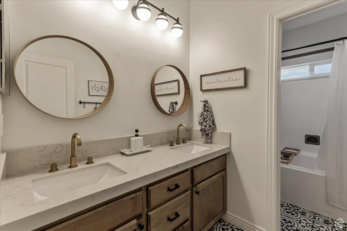 Bathroom featuring double sink, vanity with extensive cabinet space, tile floors, and shower / tub combo with curtain
