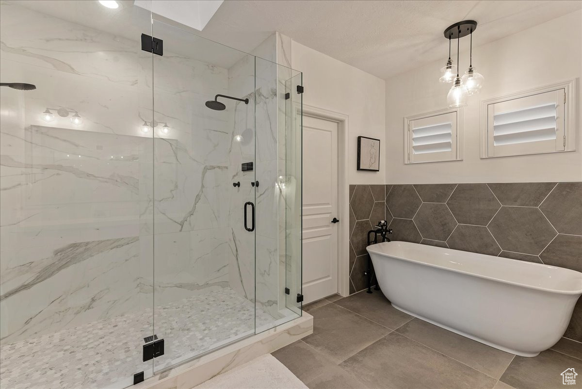 Bathroom featuring tile flooring, tile walls, and shower with separate bathtub