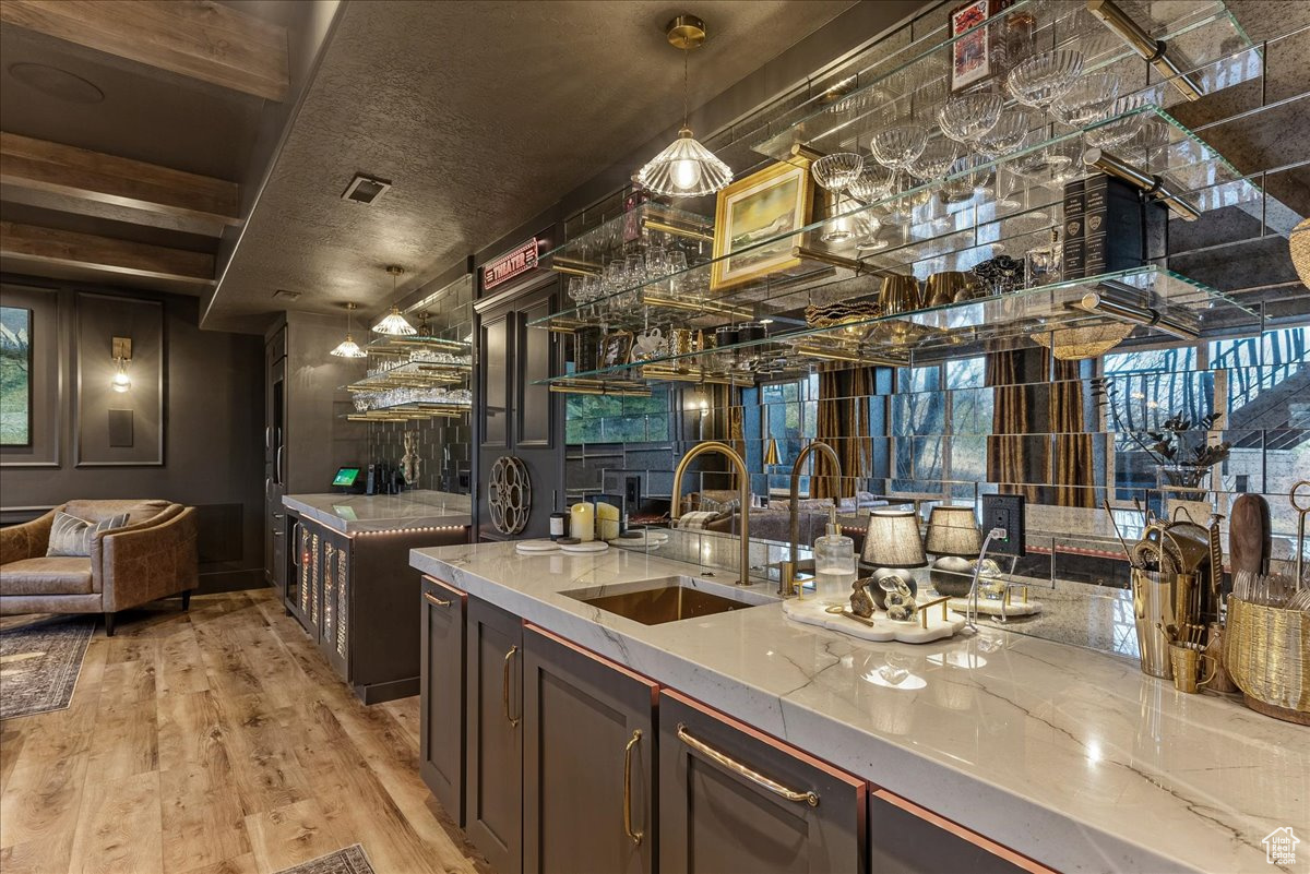 Kitchen with a fireplace, sink, dark brown cabinetry, light hardwood / wood-style flooring, and light stone counters