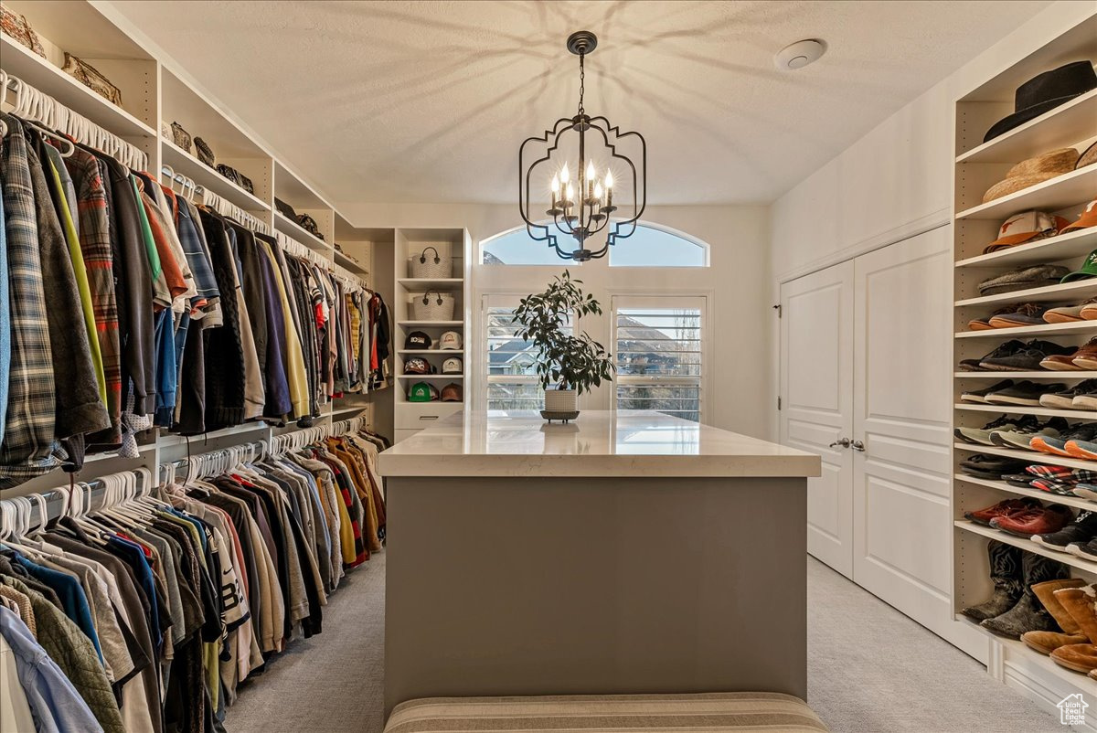Walk in closet with a chandelier and light carpet