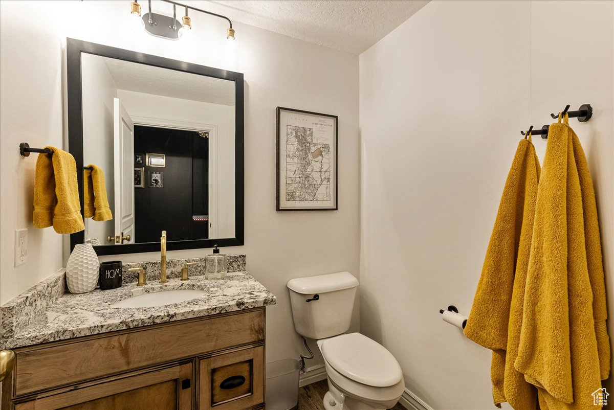 Bathroom featuring hardwood / wood-style floors, a textured ceiling, toilet, and vanity