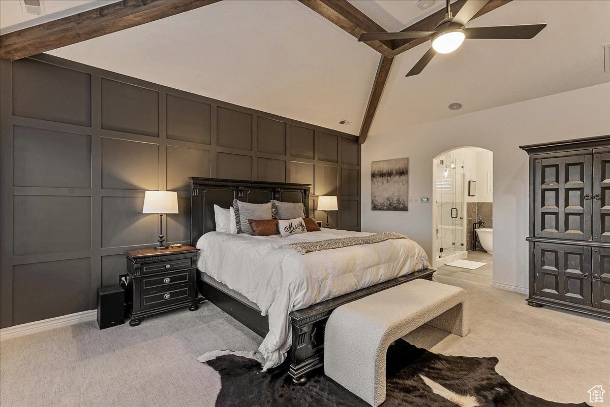 Bedroom with light colored carpet, beamed ceiling, connected bathroom, ceiling fan, and high vaulted ceiling