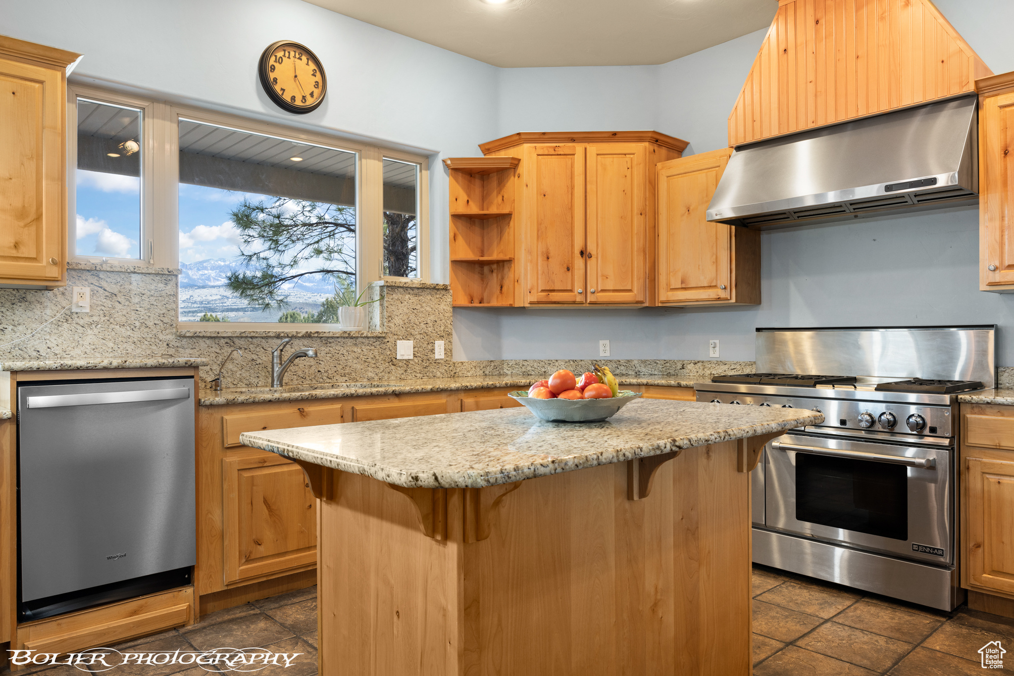 Kitchen featuring professional-grade stainless steel appliances, tasteful backsplash, dark tile flooring, and wall chimney exhaust hood