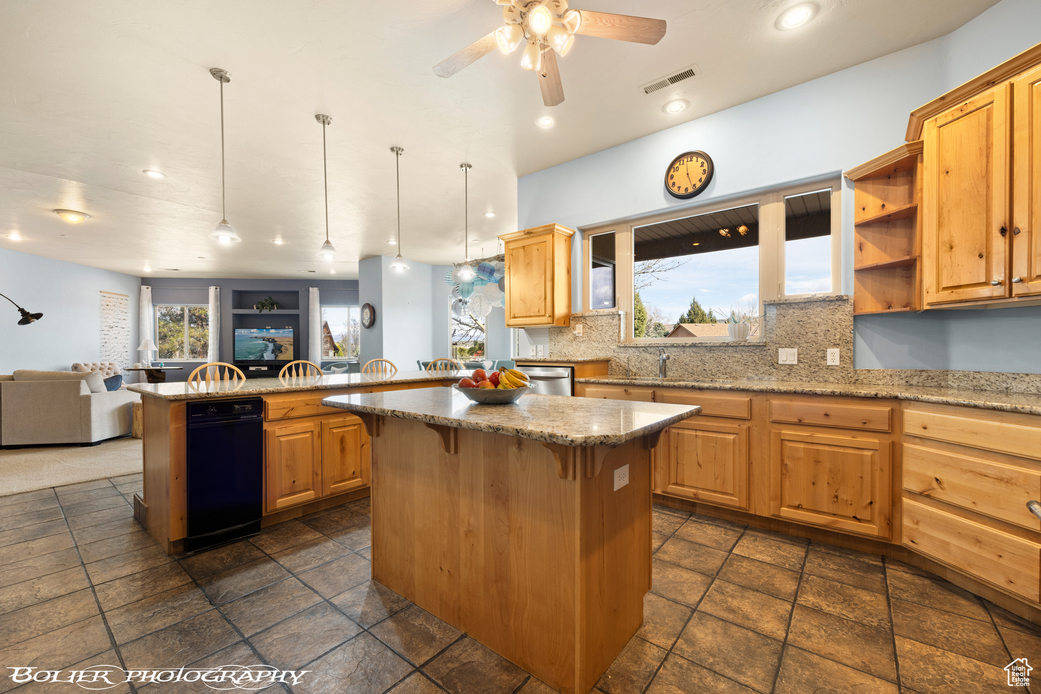 Kitchen featuring ceiling fan, black dishwasher, backsplash, a center island, and hanging light fixtures