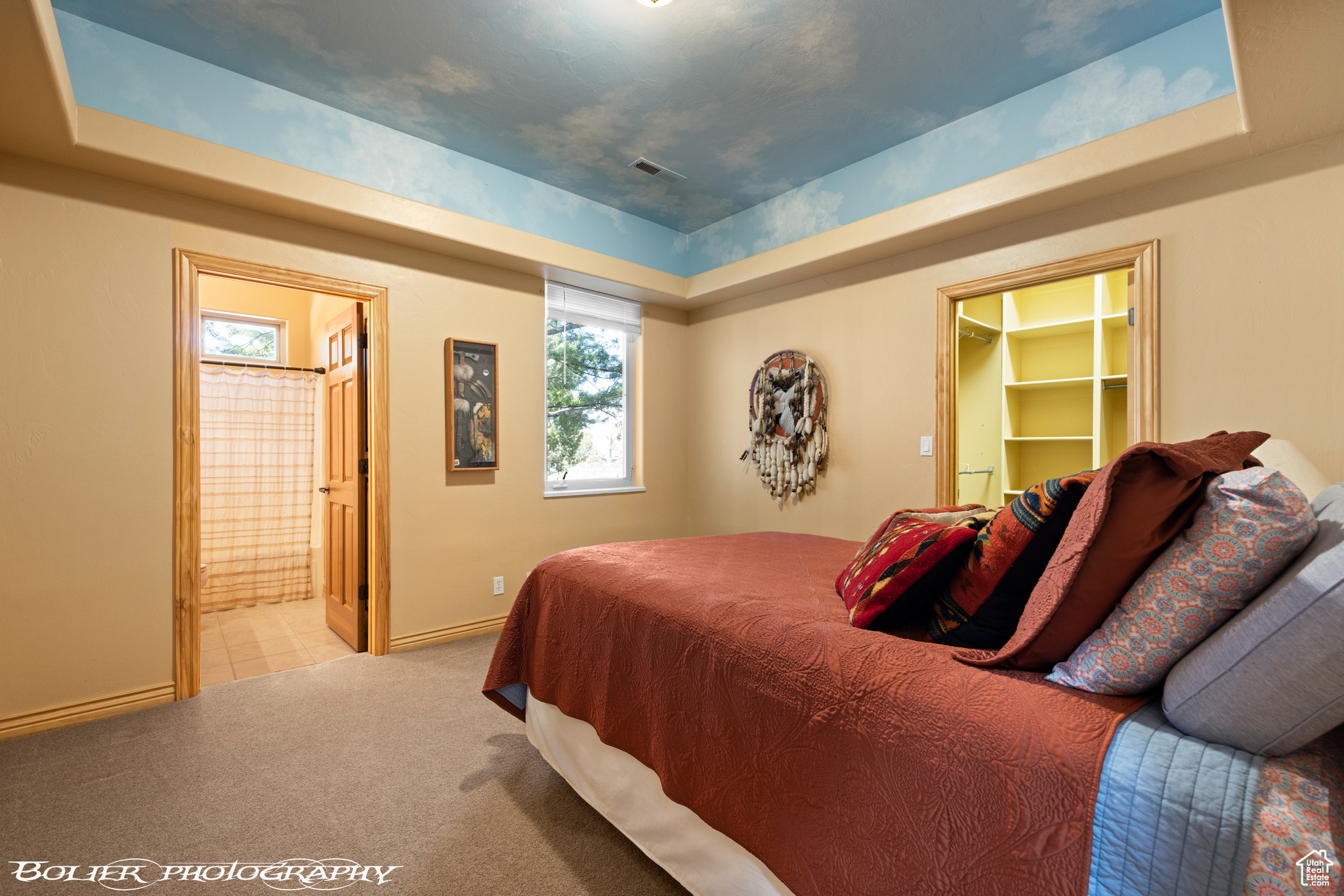 Carpeted bedroom featuring ensuite bath, a spacious closet, a closet, and a tray ceiling