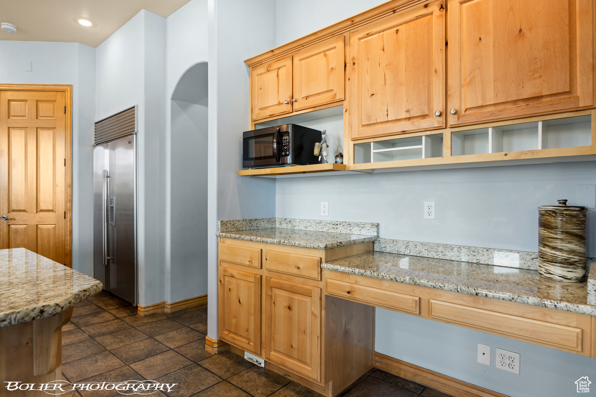 Kitchen with appliances with stainless steel finishes, dark tile floors, and light stone counters