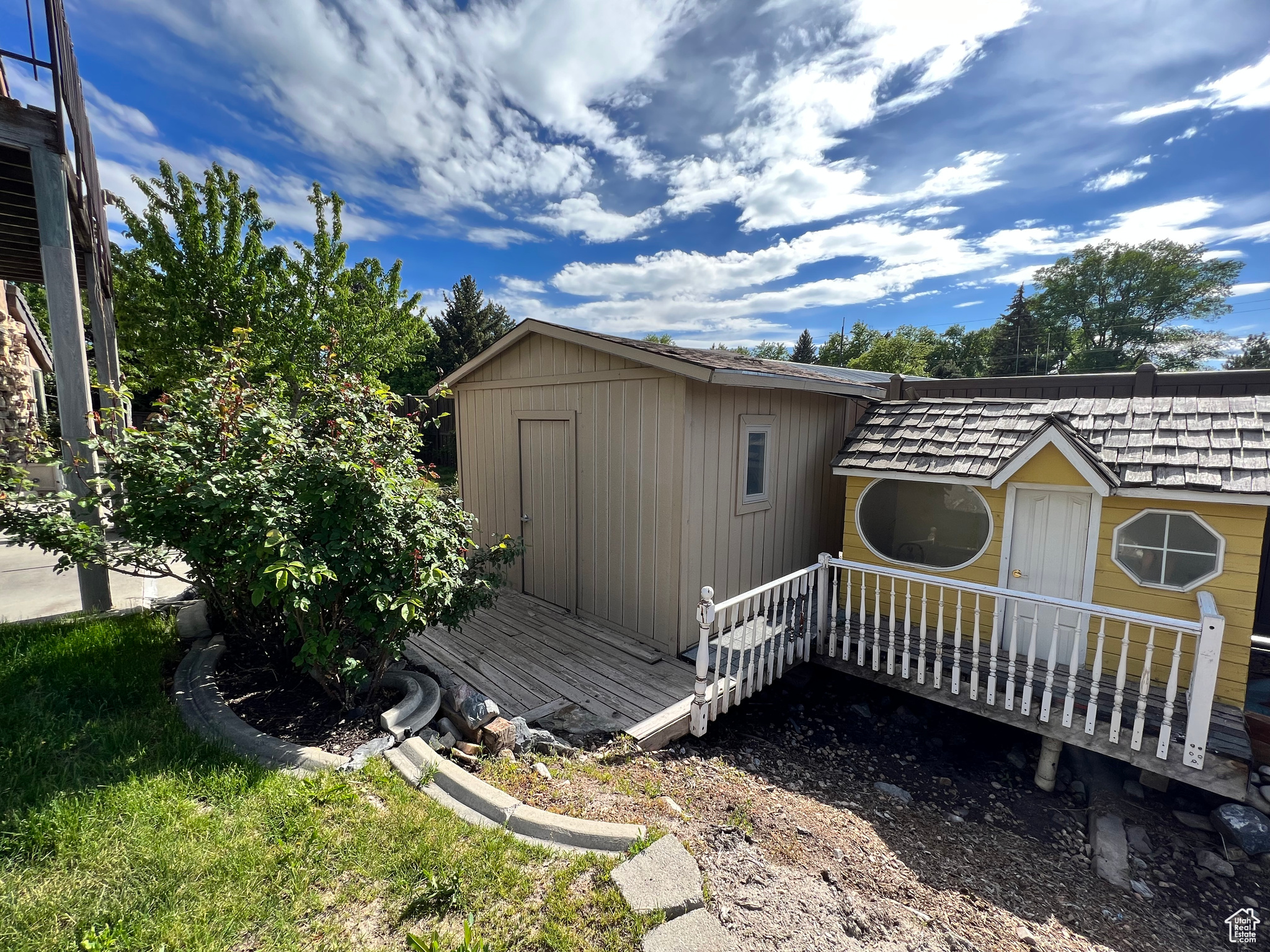 View of side of home featuring a storage unit and a deck