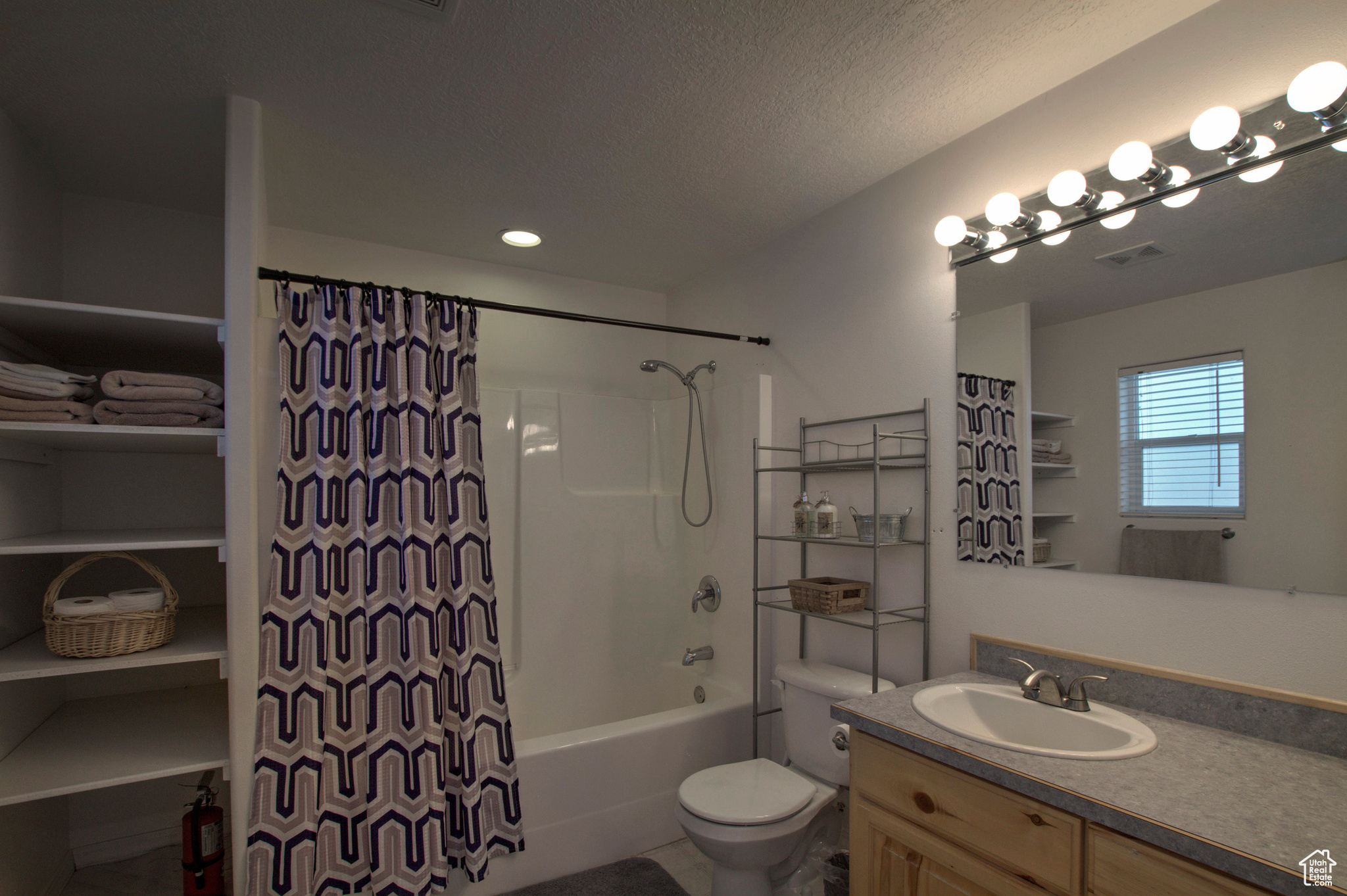 Full bathroom featuring a textured ceiling, shower / tub combo with curtain, tile flooring, vanity, and toilet