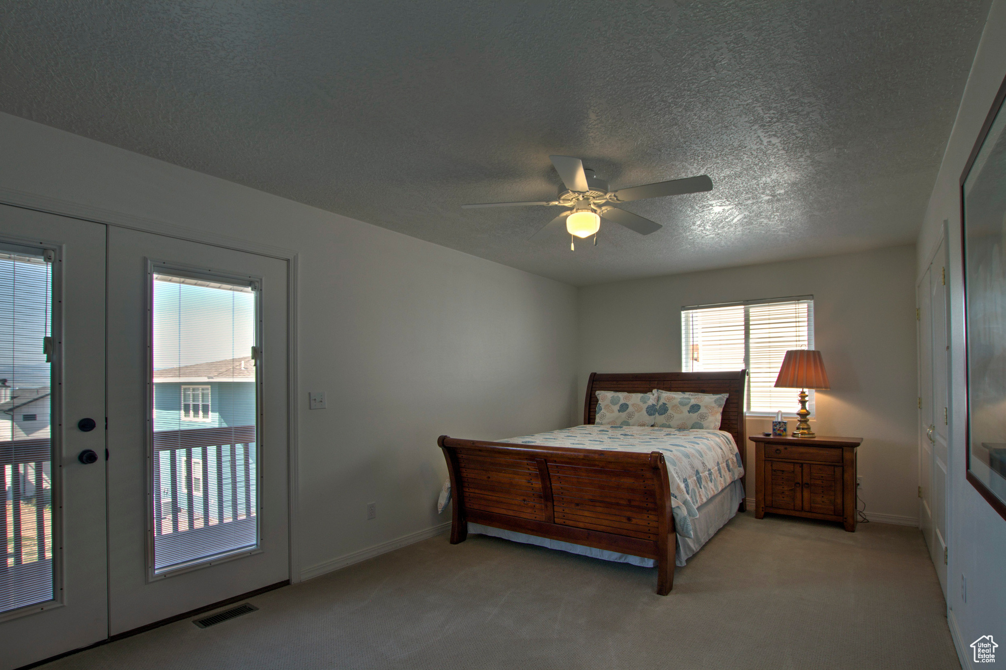 Bedroom featuring light colored carpet, french doors, ceiling fan, a textured ceiling, and access to exterior