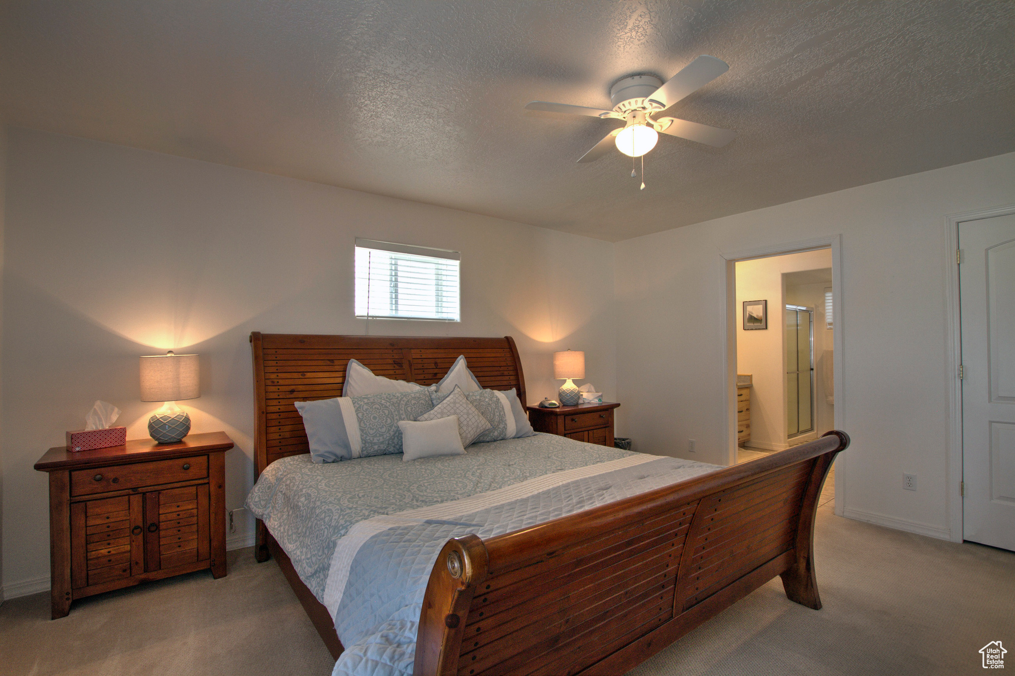 Bedroom featuring light colored carpet, ensuite bathroom, a textured ceiling, and ceiling fan