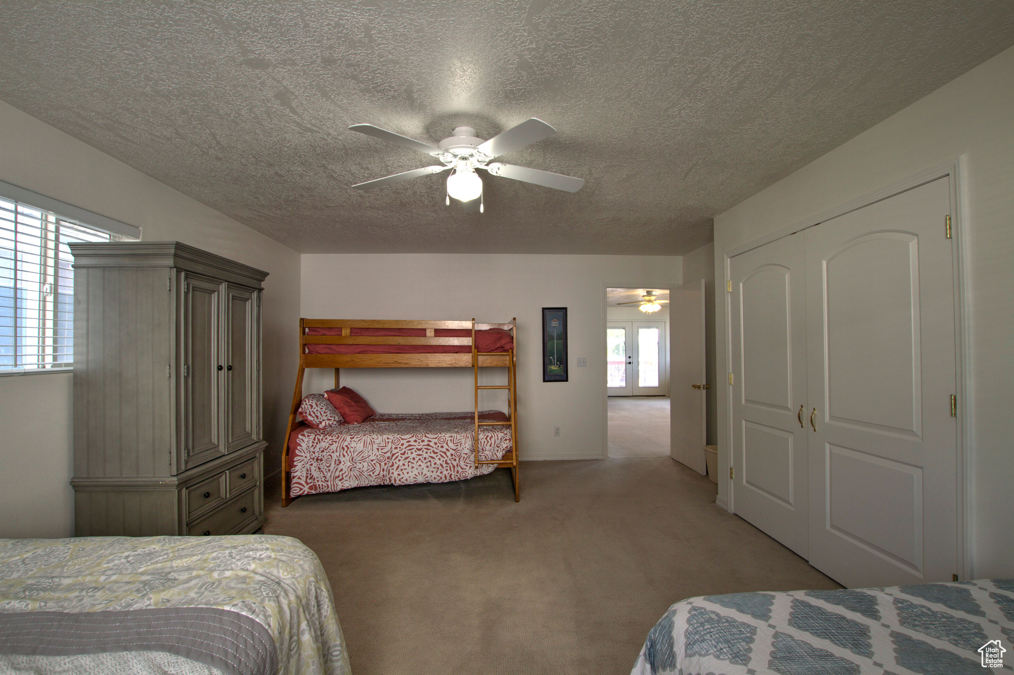 Bedroom with light colored carpet, multiple windows, ceiling fan, and a closet