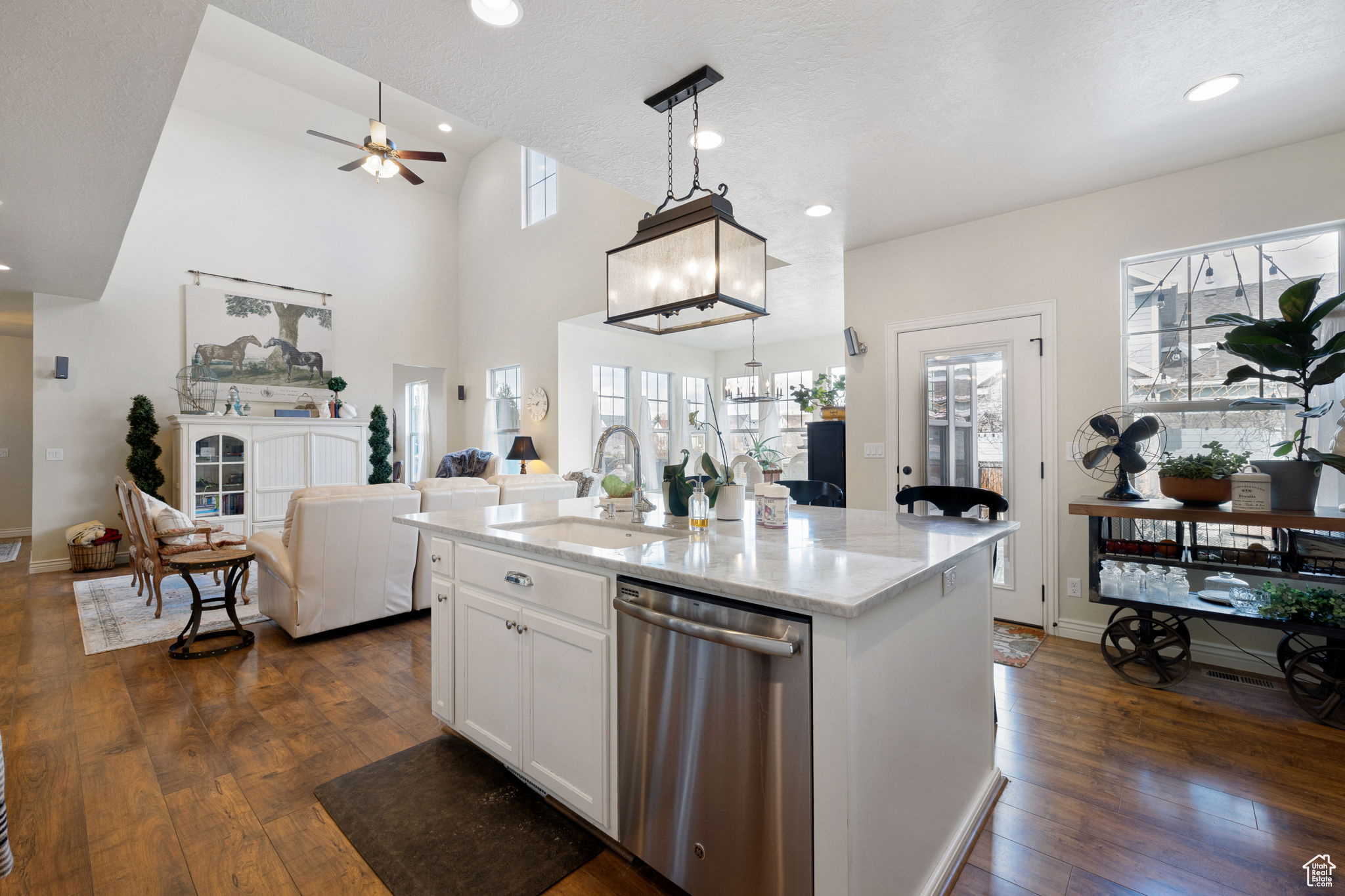 Kitchen with hanging light fixtures, dark hardwood / wood-style flooring, dishwasher, and sink