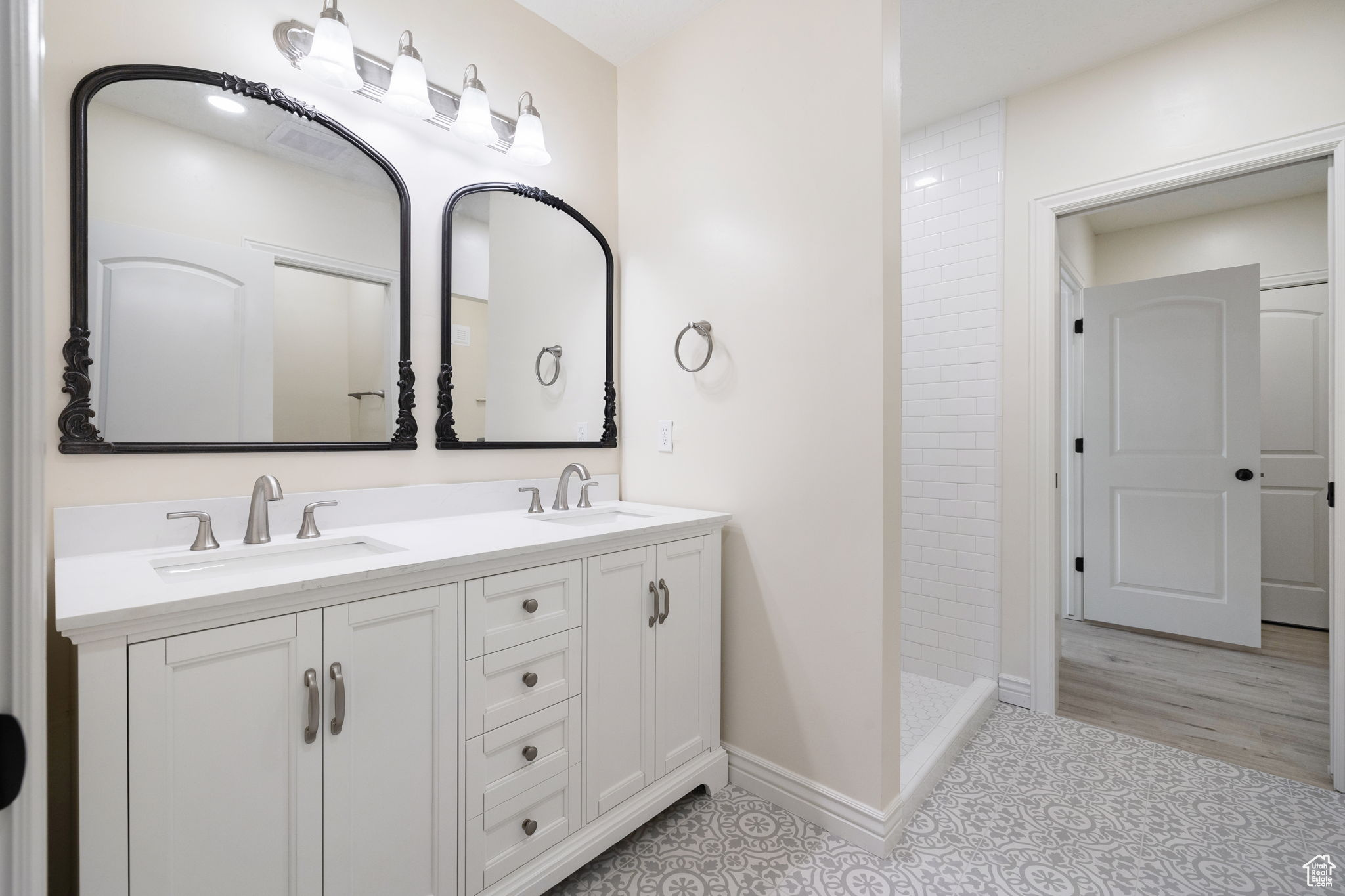 Bathroom with double vanity, tile floors, and a tile shower and second basement laundry.