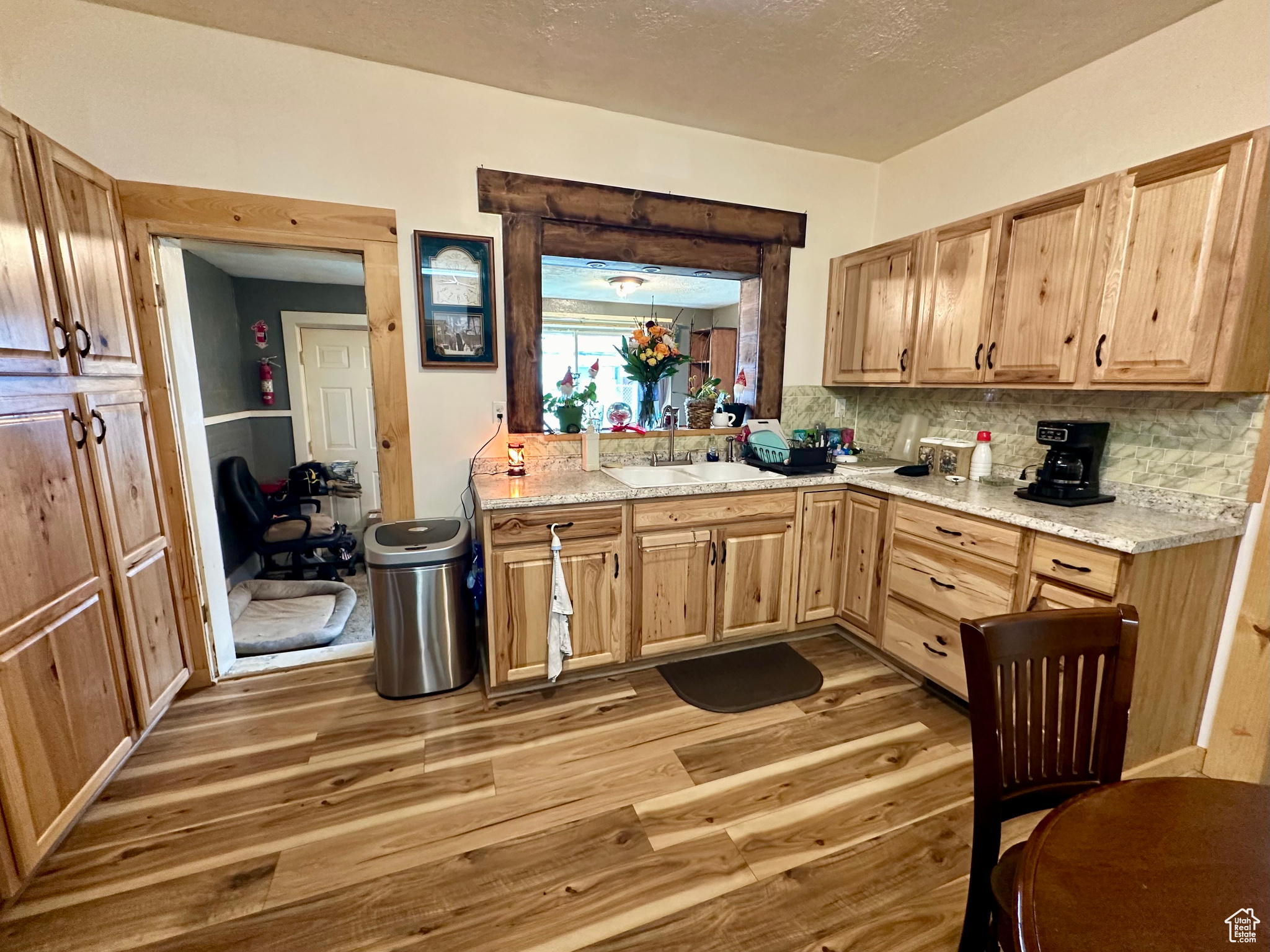 Kitchen with backsplash, light stone counters, sink, and hardwood / wood-style floors